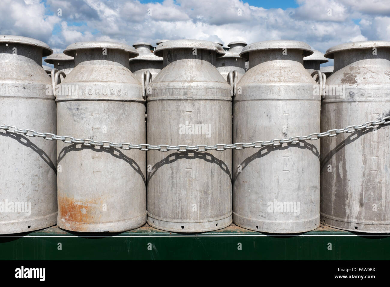 Eine Reihe von zehn Gallonen Aluminium Milchkannen gestapelt auf der Rückseite eines LKW. Dorset, England, Vereinigtes Königreich Stockfoto