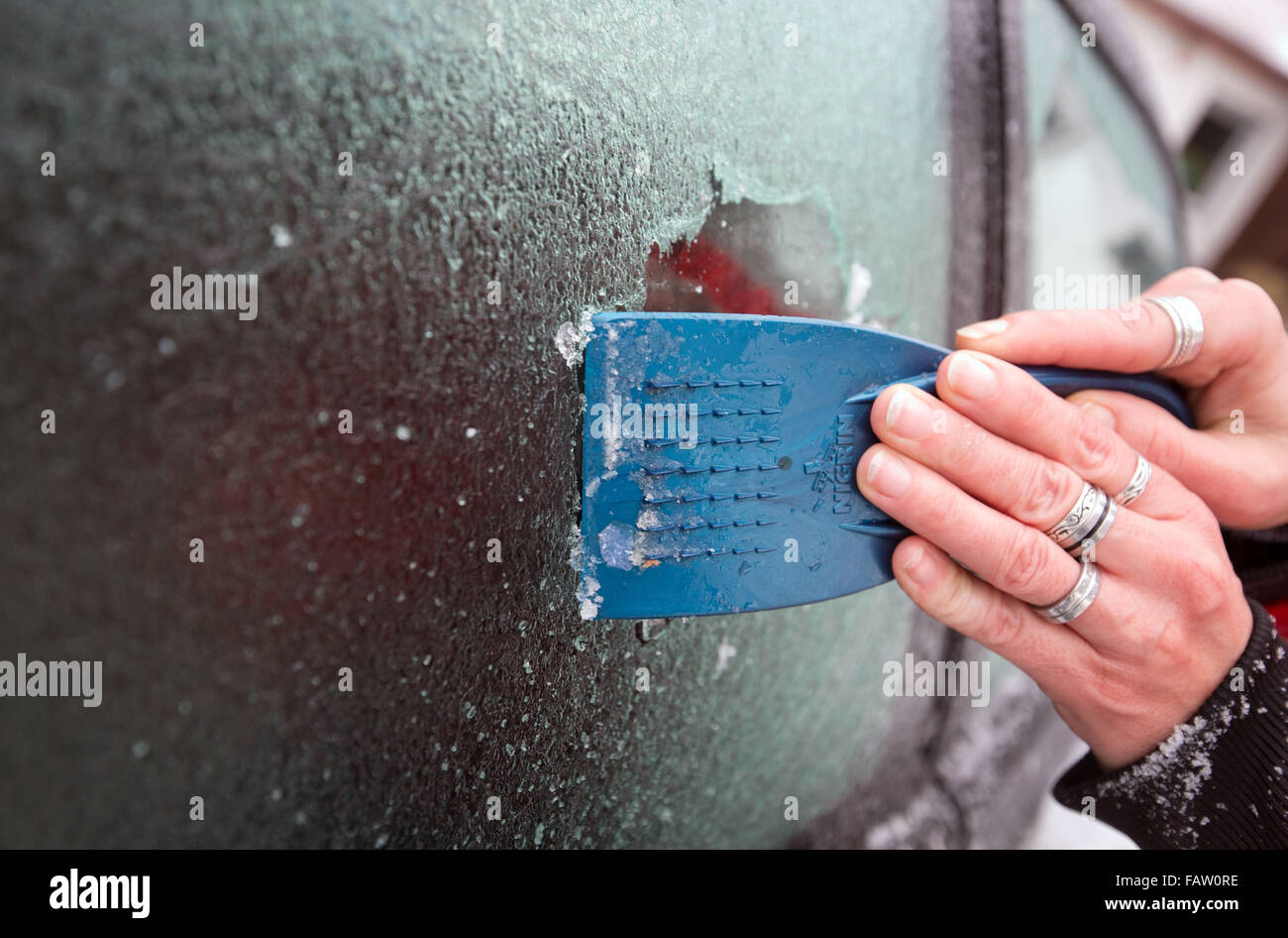 Eine Frau kratzt Eis aus dem Fenster ihres Autos in Lübbecke, Deutschland, 5. Januar 2016. Regionalen Temperaturen gemischt mit leichtem Regen schwebte um den Gefrierpunkt in der vorherigen Nacht. Foto: OLIVER KRATO/dpa Stockfoto