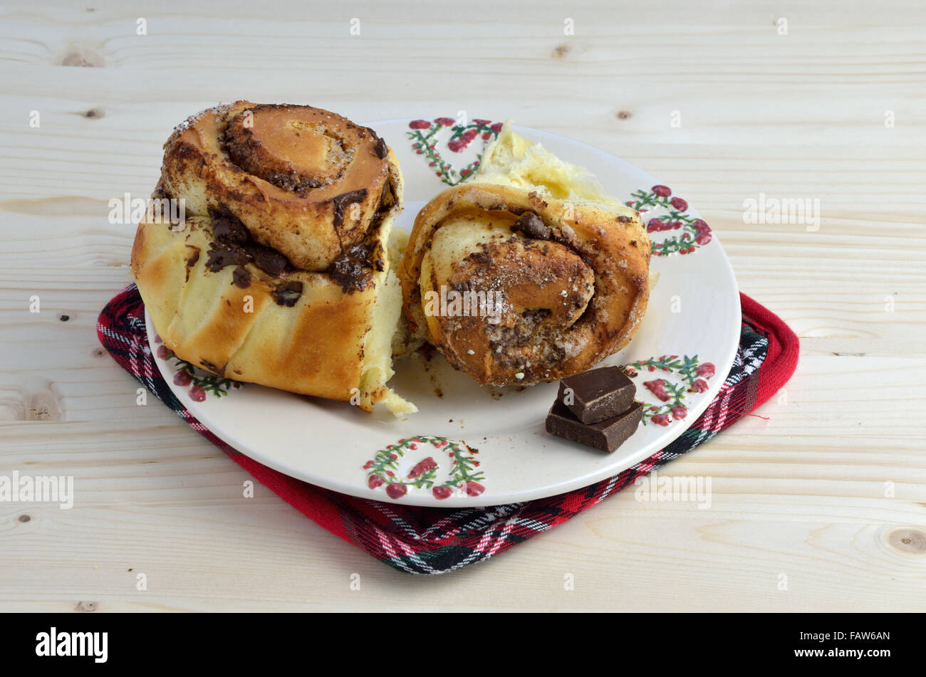 Frische Zimtschnecken flauschige mit Schokolade auf einem Porzellanteller am Holztisch Stockfoto
