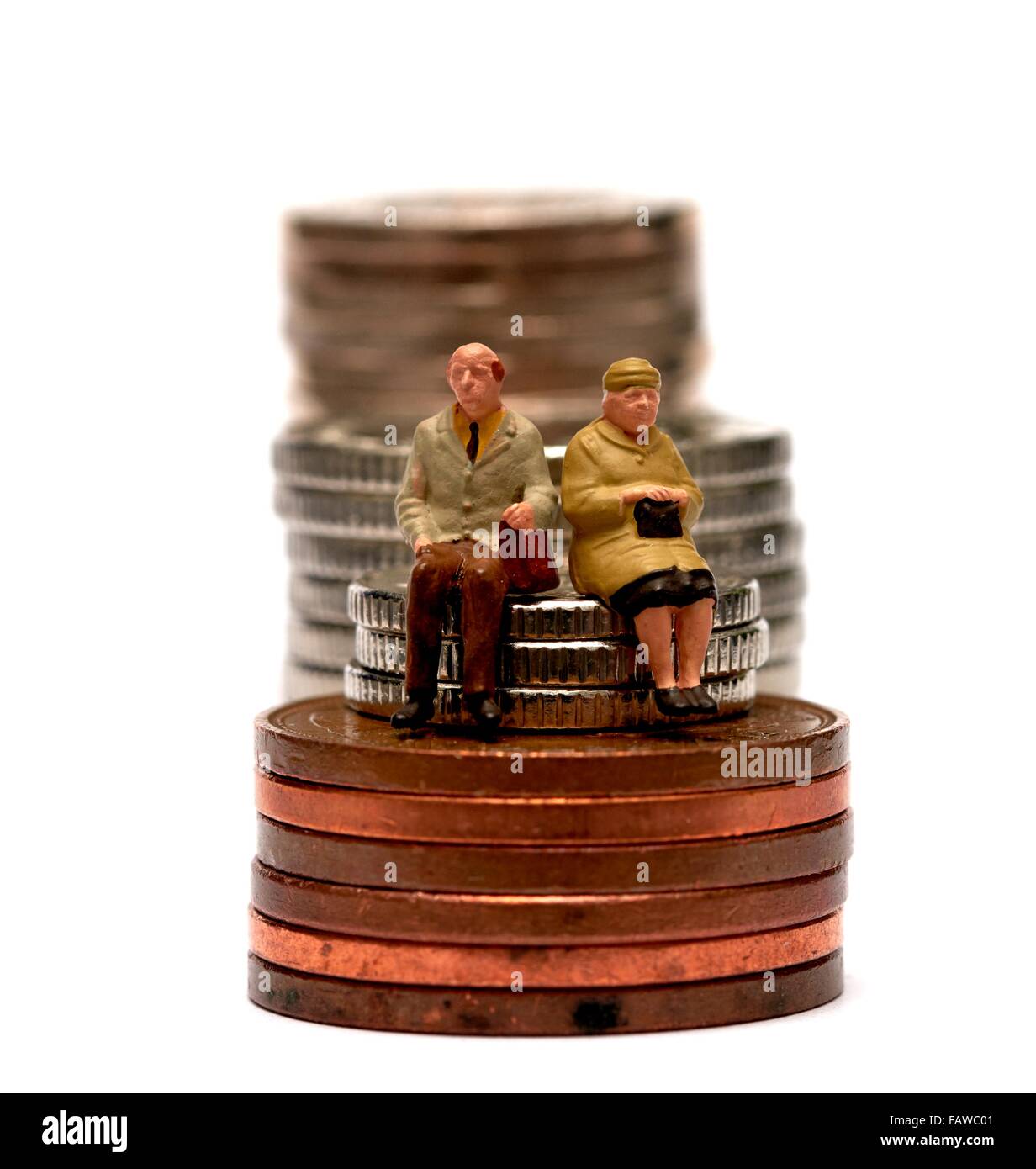 2 Miniatur Menschen Rentner sitzen auf Stapel von britischen Geld Münzen Stockfoto