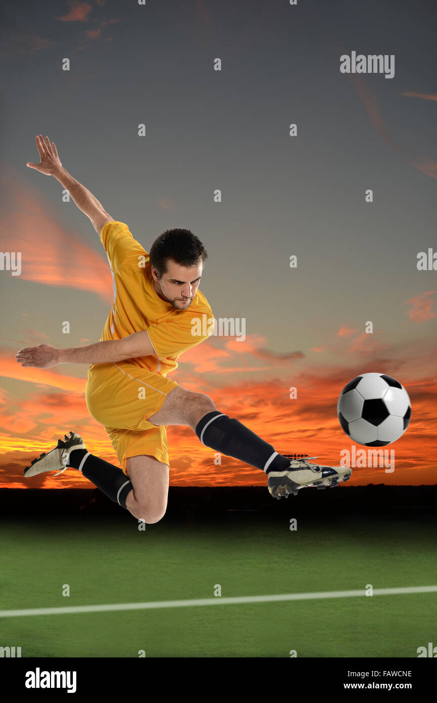 Junge Fußballer treten Ball über Sonnenuntergang Hintergrund Stockfoto