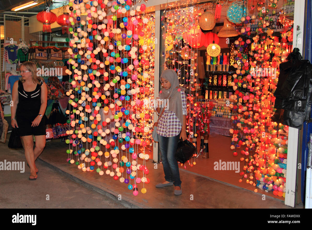 Ein lokaler Verkaufsstand voller Lichter, an dem Touristen vorbeilaufen, auf Penang Island, Penang, Malaysia Stockfoto