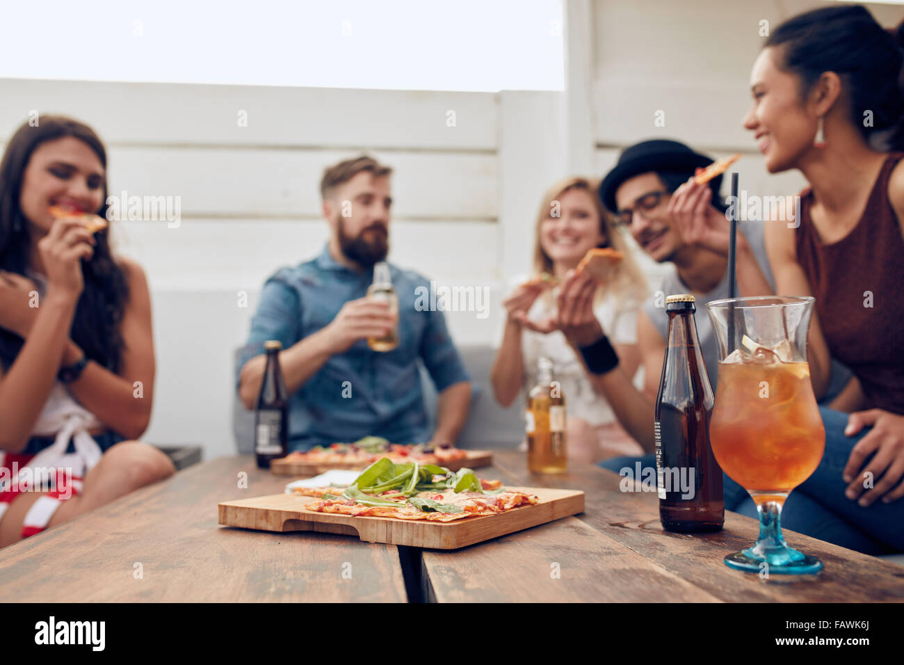 Gruppe von multi-ethnischen Freunden genießen Sie Pizza und Bier in der Partei. Junge Menschen mit einer Party. Pizza und cocktail liegend o im Fokus Stockfoto