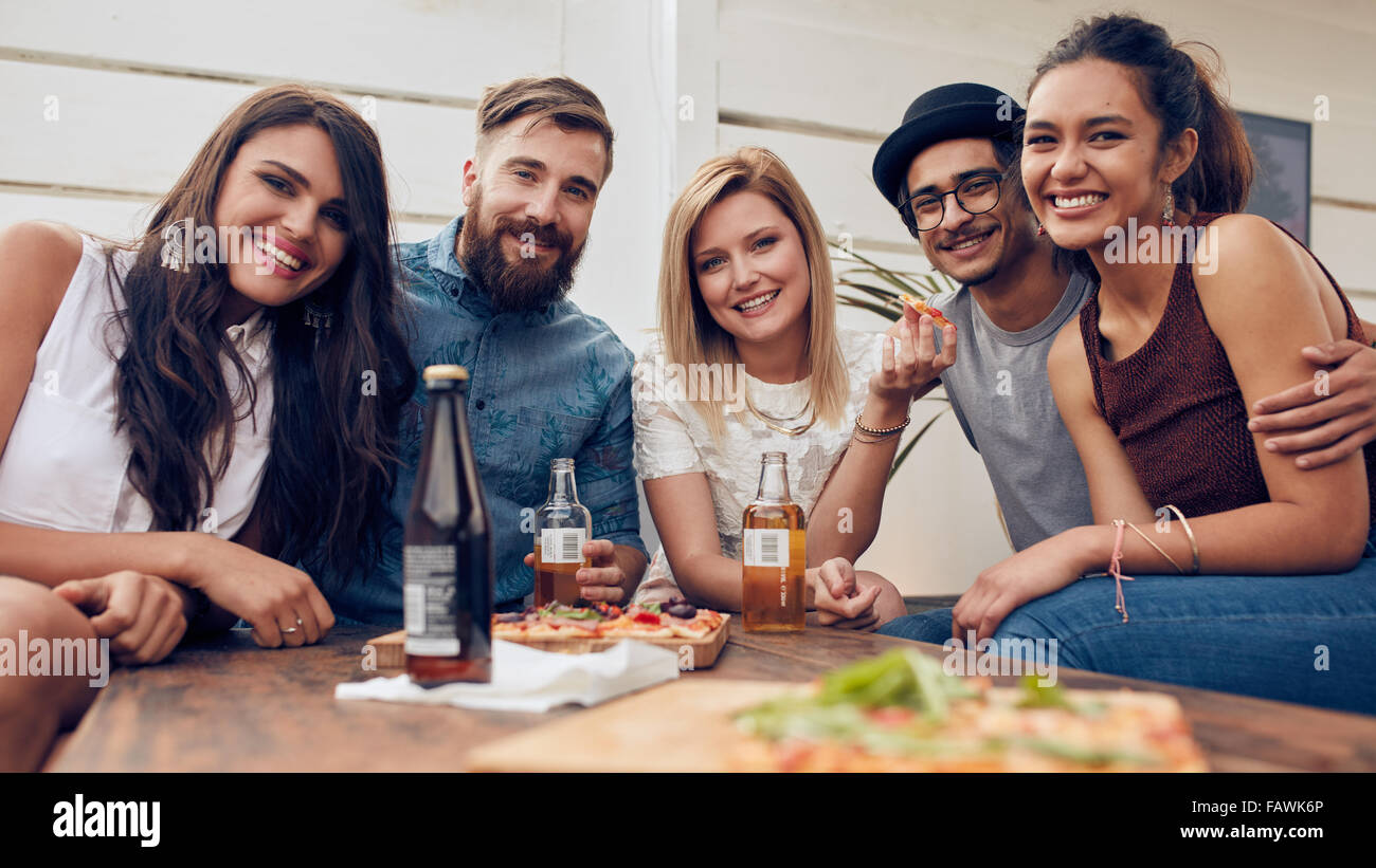 Gruppenbild der jungen Freunde versammelten sich am Tisch auf einer Party auf dem Dach. Gemischtrassig Jugendlichen Blick auf Kamera und smi Stockfoto
