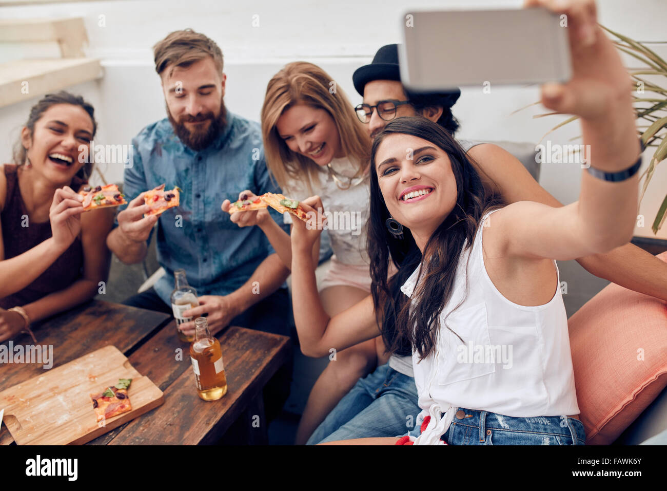Gruppe von Freunden nehmen Selfie auf einem Smartphone. Junge Leute Essen Pizza auf der Dachterrasse Partei nehmen Selfie. Stockfoto
