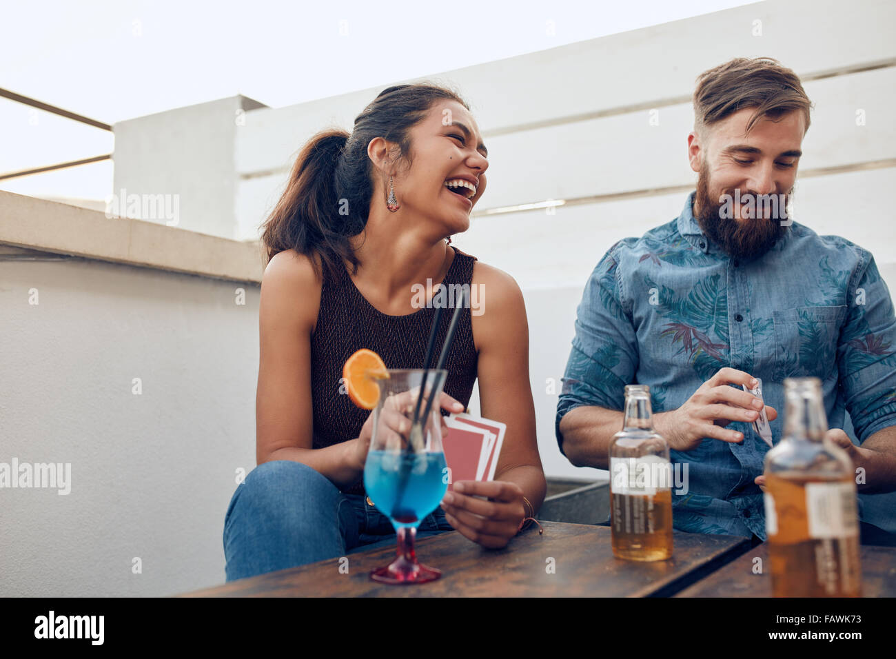 Paar von einem Tisch gefeiert und Spielkarten sitzt. Glückliche junge Mann und Frau Spielkarten während einer Party. Stockfoto