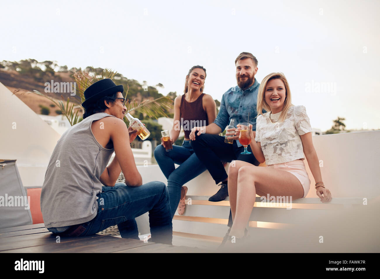 Schuss glückliche junge Menschen sitzen zusammen mit Getränken. Freunde, die Spaß an Party. Top Party Cocktail Dach. Stockfoto