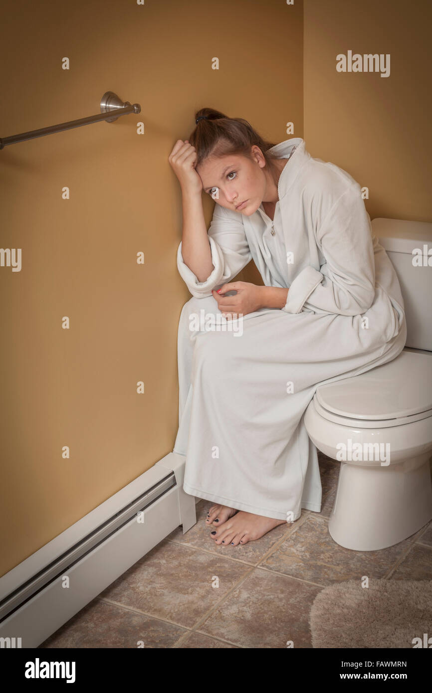 Teenager-Mädchen sitzen im Bad auf dem Toilettensitz suchen unglücklich Stockfoto