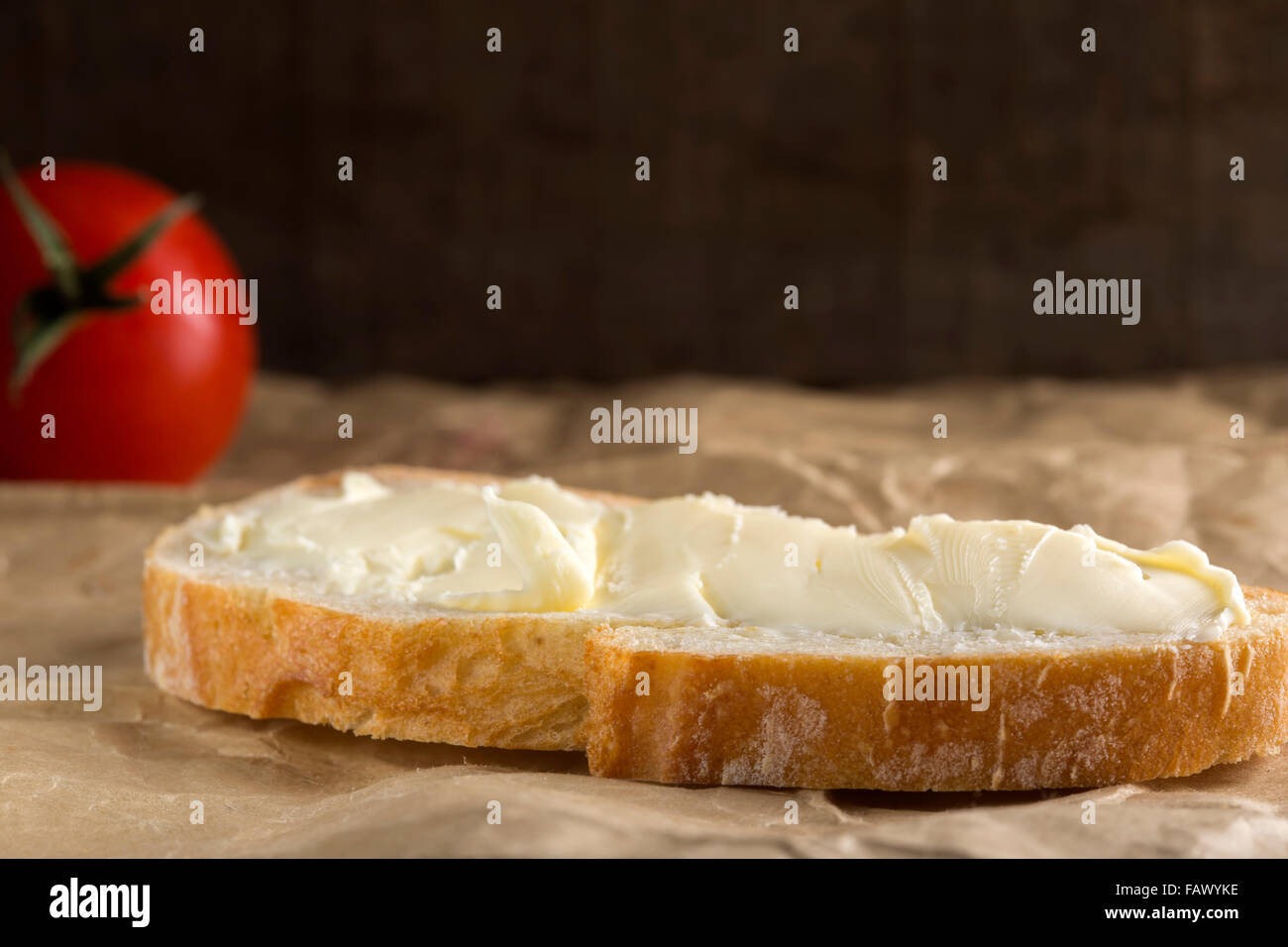 Frisches Brot und selbst gemachter Butter auf Papierhintergrund Stockfoto