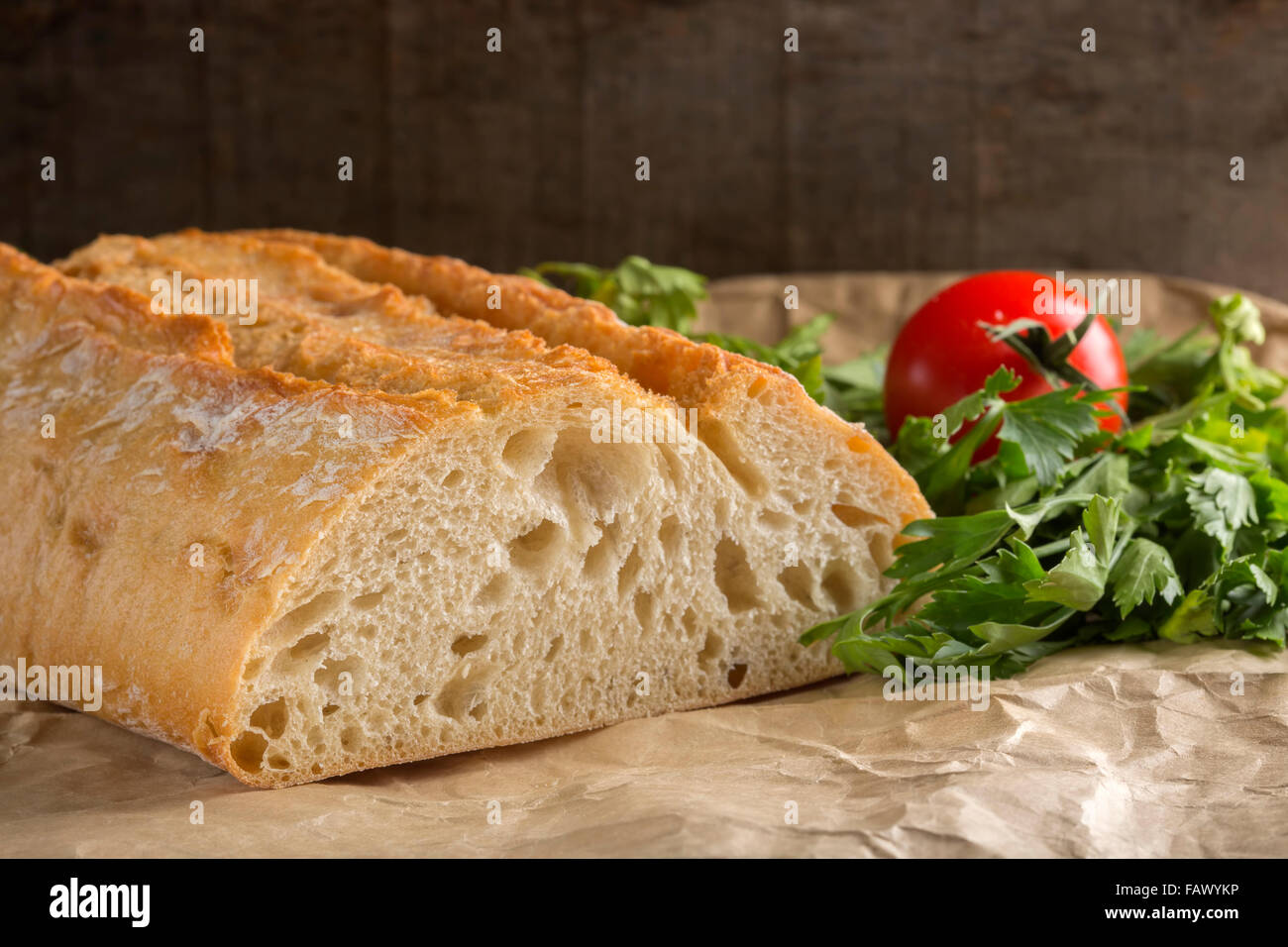 Frische hausgemachte Brot auf Papier mit Petersilie und Tomate Stockfoto