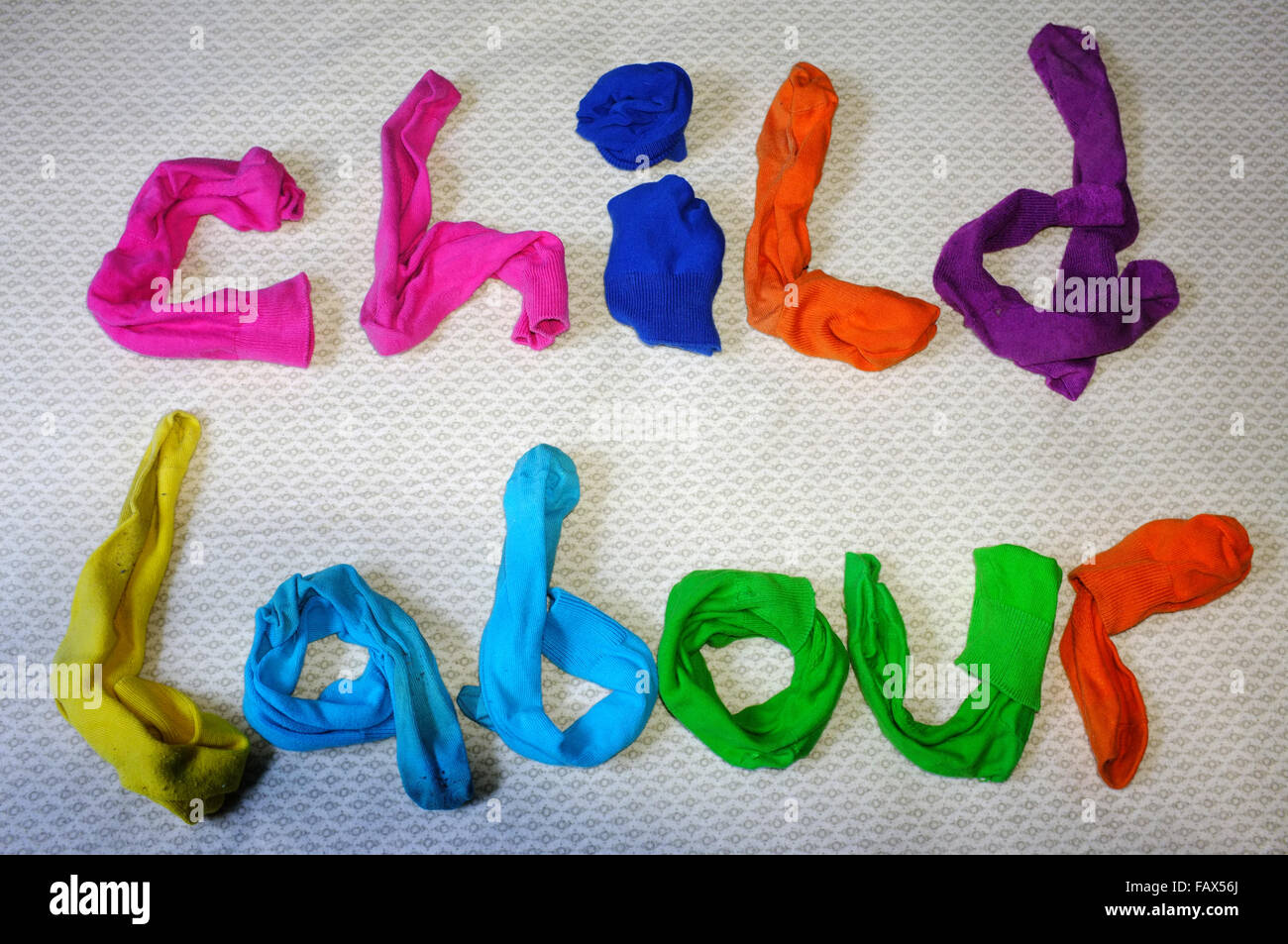 Die Worte Kinderarbeit hergestellt aus bunten Socken Handauflegen einen Bettbezug. Stockfoto