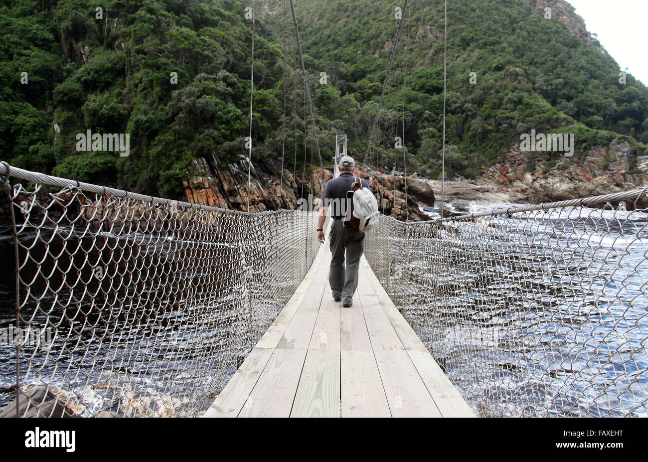 Touristen über die Hängebrücke über Storms River Mouth im Tsitsikamma National Park in Südafrika Stockfoto