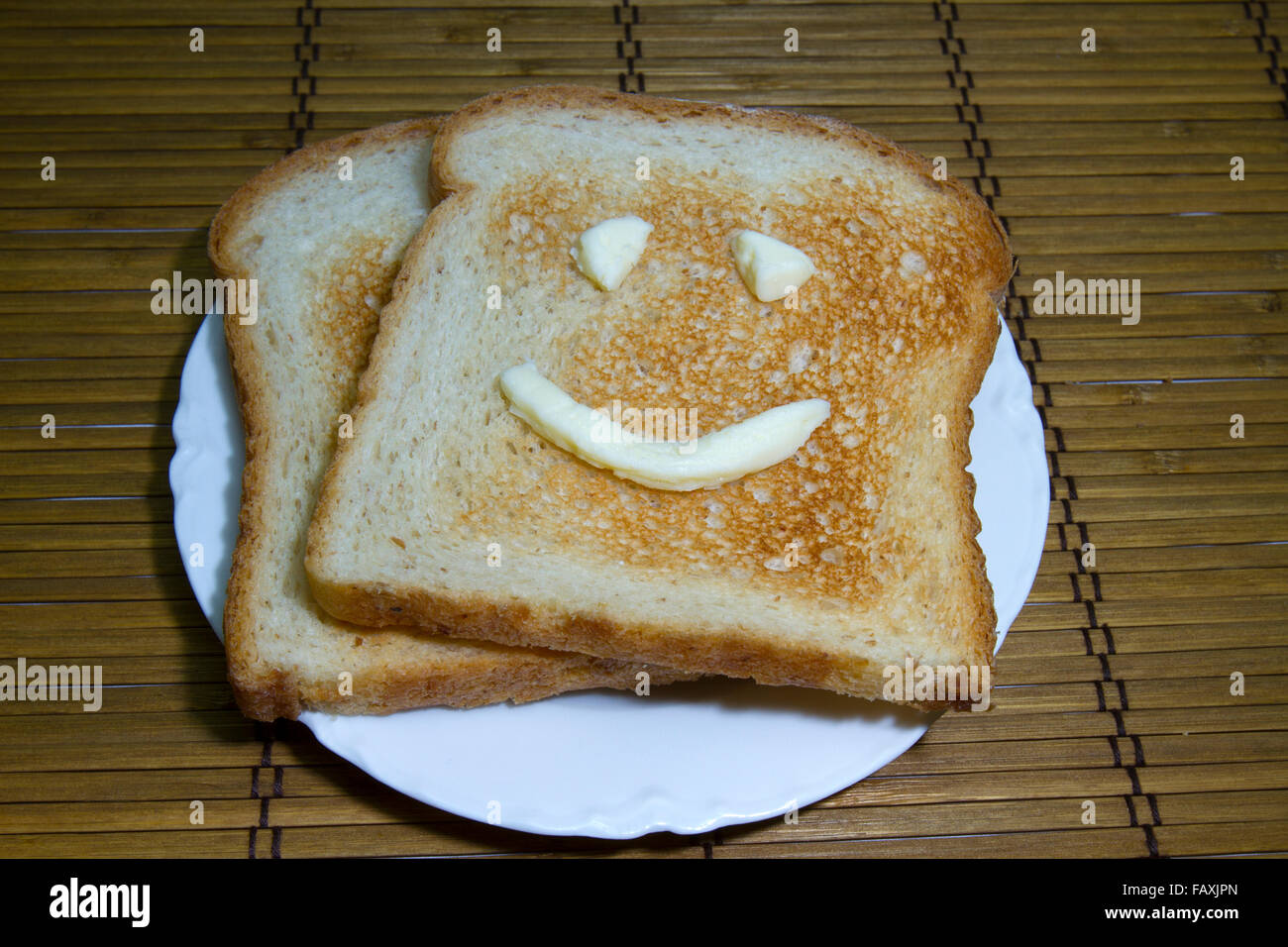 Toast auf weißen Teller mit Butter Augen und Lächeln. Stockfoto