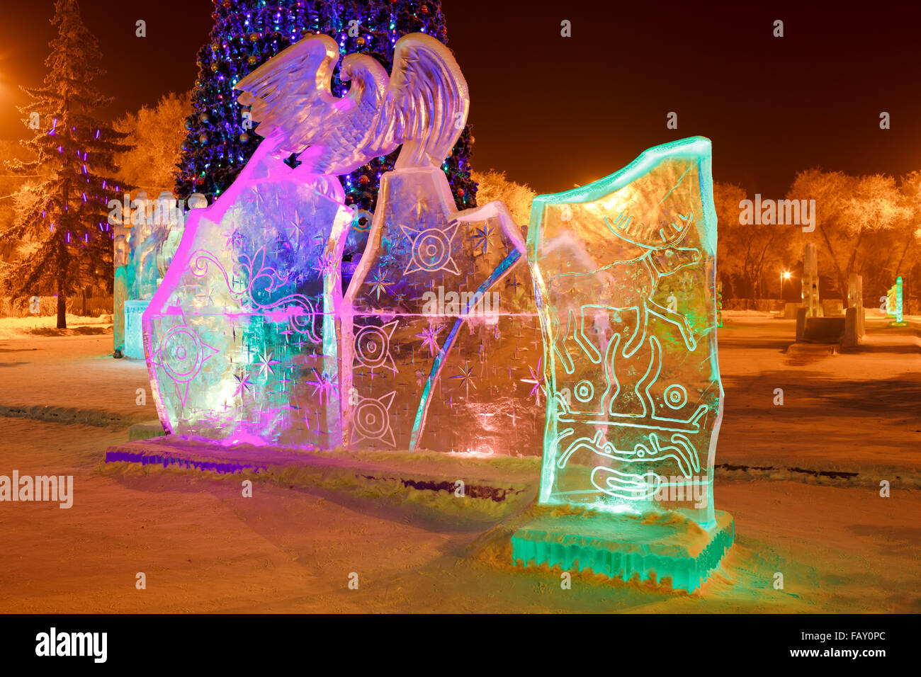 Eis-Skulptur im Stadtpark an Weihnachten und Silvester mit Höhlenmalereien von Hirschen, Fabelwesen, solar Schilder, Petroglyphen. Nachts beleuchtet. Stockfoto