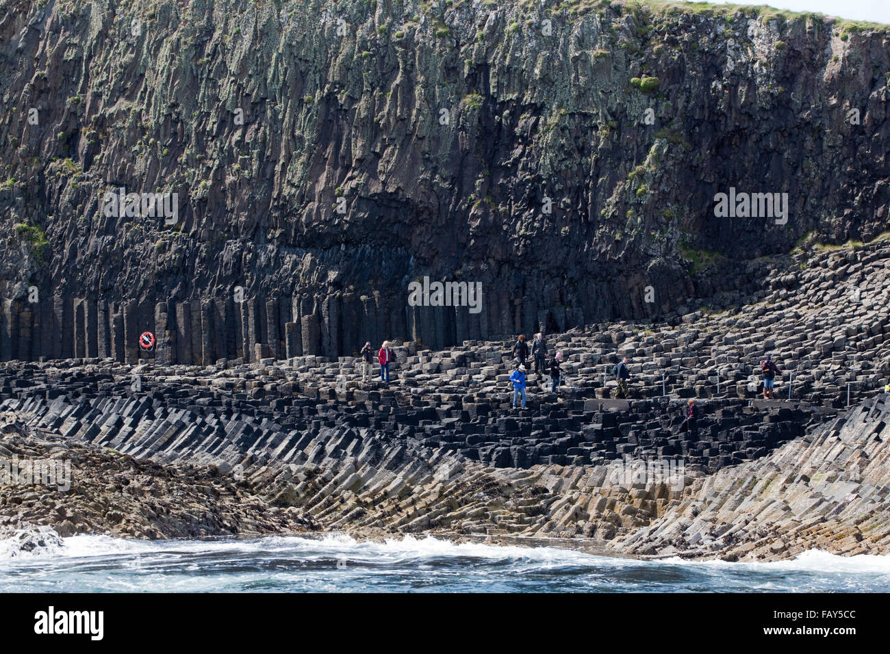 Sechseckigen Basaltsäulen über Meerwasser ausgesetzt. Touristen auf Fußweg neben Fingal's Cave. Staffa. Westlich von Schottland Stockfoto