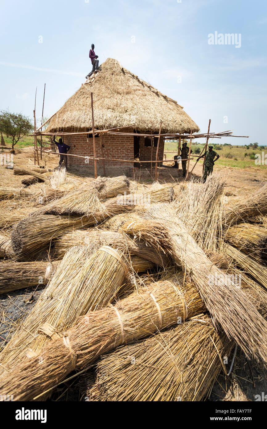 Arbeitnehmer ein Grasdach reetgedeckten Gebäude; Uganda Stockfoto