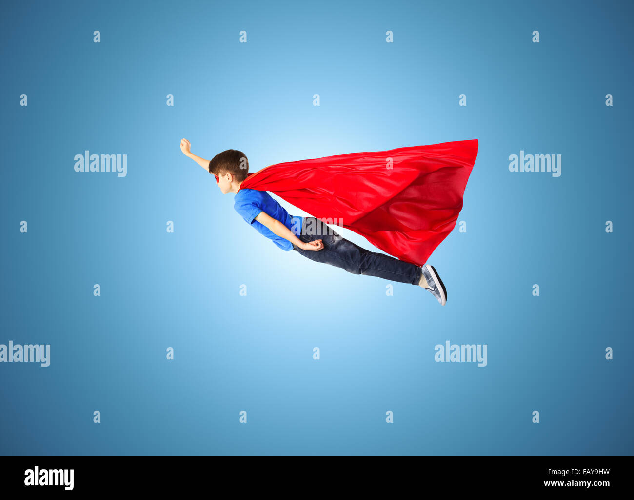 Junge im roten Superhelden Cape und Maske, die fliegen in der Luft Stockfoto