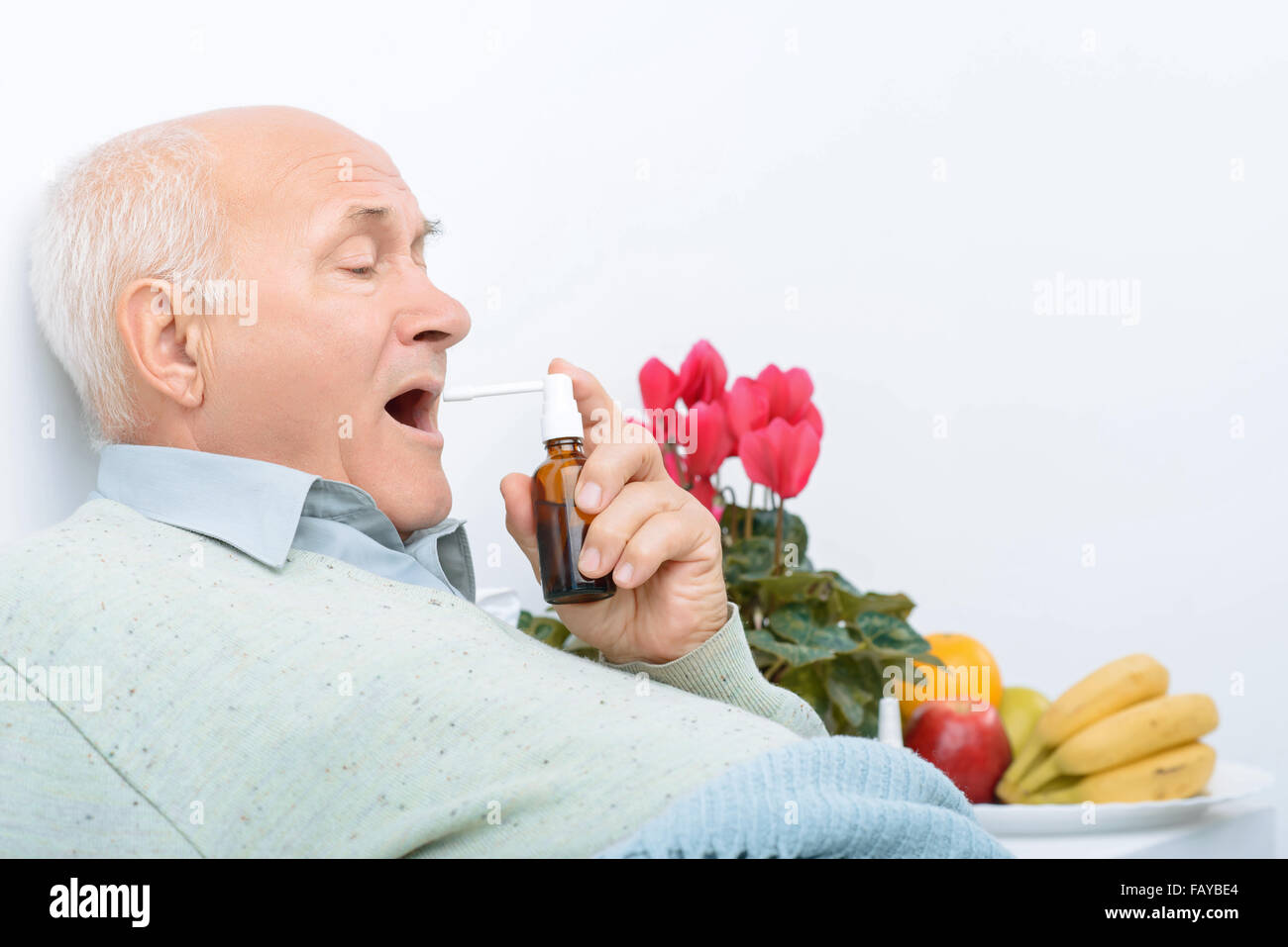 Müden senior Gentleman nutzt seine Halsschmerzen-Spray. Stockfoto