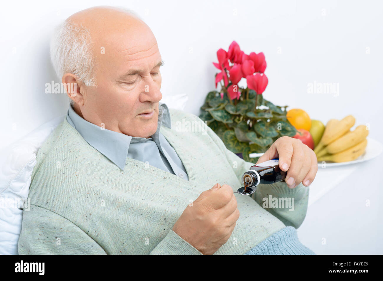 Senior im Alter Mann gießt sich Hustensaft. Stockfoto