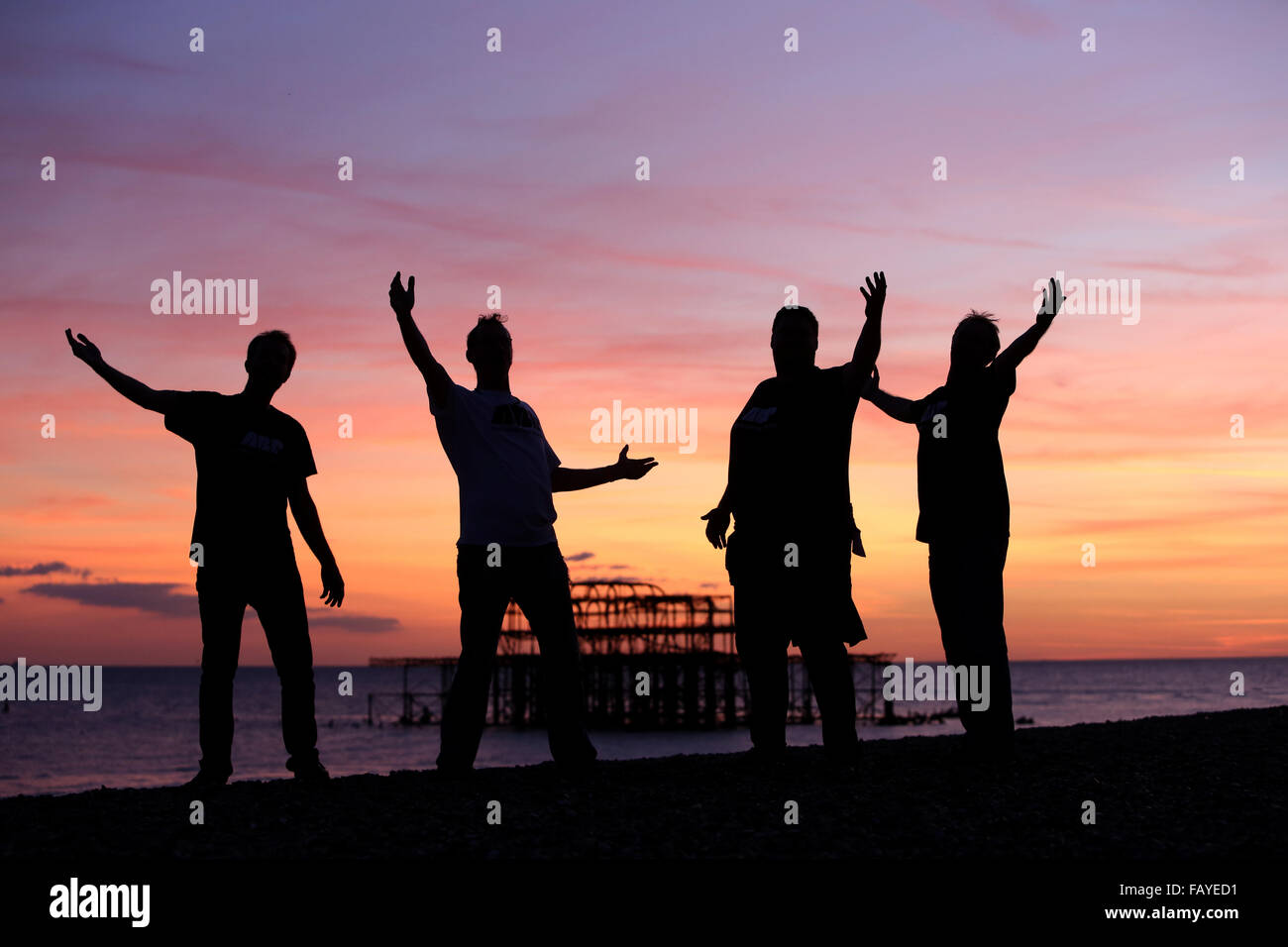 Vier Sänger auf Brighton Beach mit dem West Pier im Hintergrund abgebildet werden, wenn die Sonne untergeht. Brighton, East Sussex, UK. Stockfoto