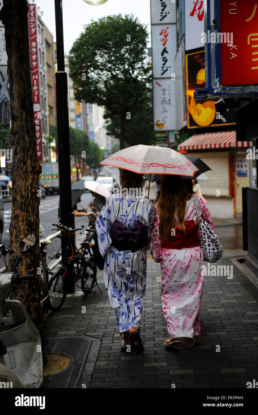 zwei Frauen tragen Yukata Wandern im goldenen Gai Bezirk unter dem Regen Tokio Japan Stockfoto