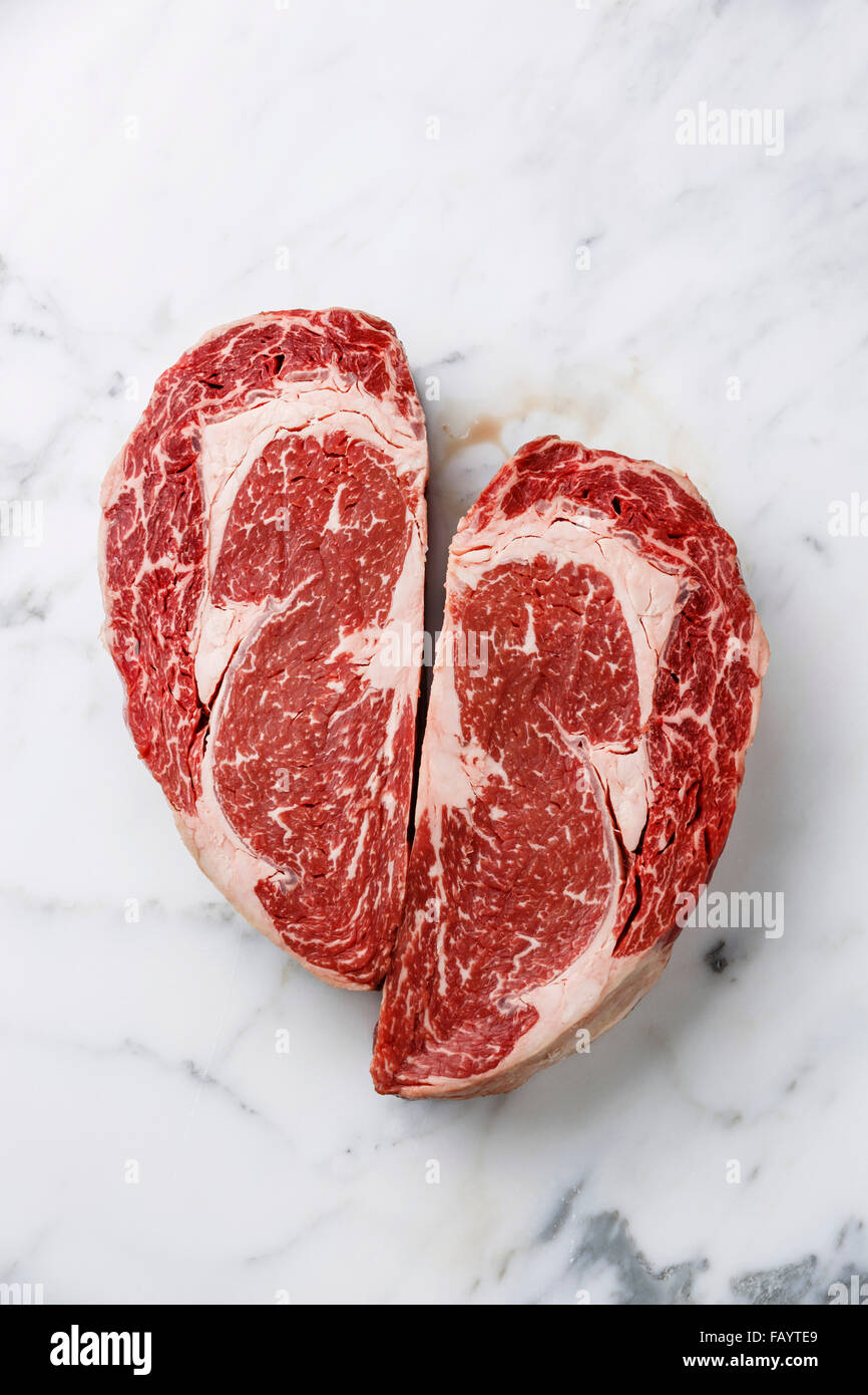 Herzform rohes Frischfleisch Ribeye Steak auf weißem Marmor Hintergrund Stockfoto