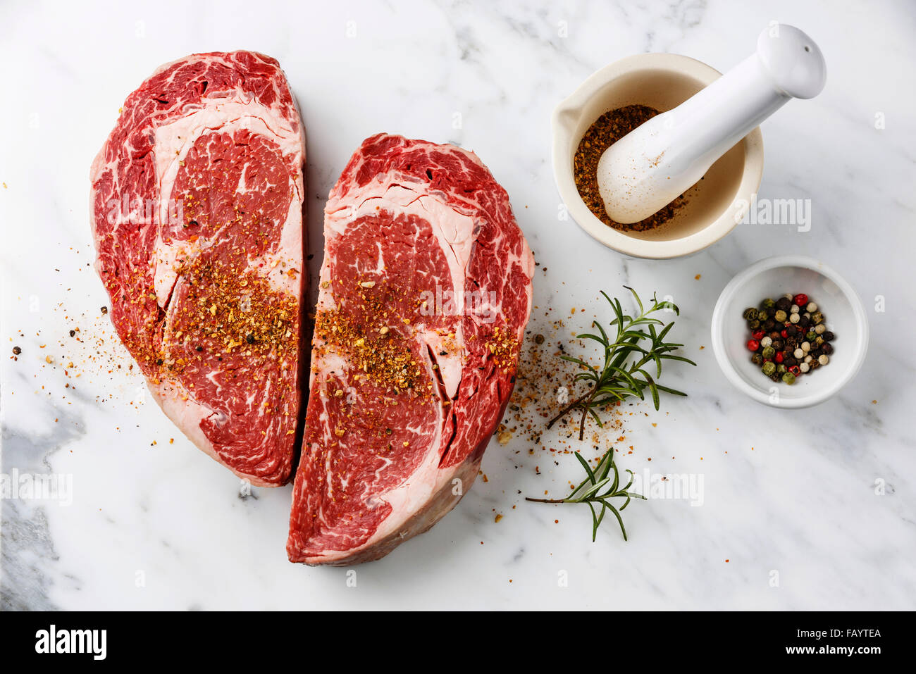 Herzform rohes Frischfleisch Ribeye Steak mit Pfeffer und Rosmarin auf weißem Marmor Hintergrund Stockfoto