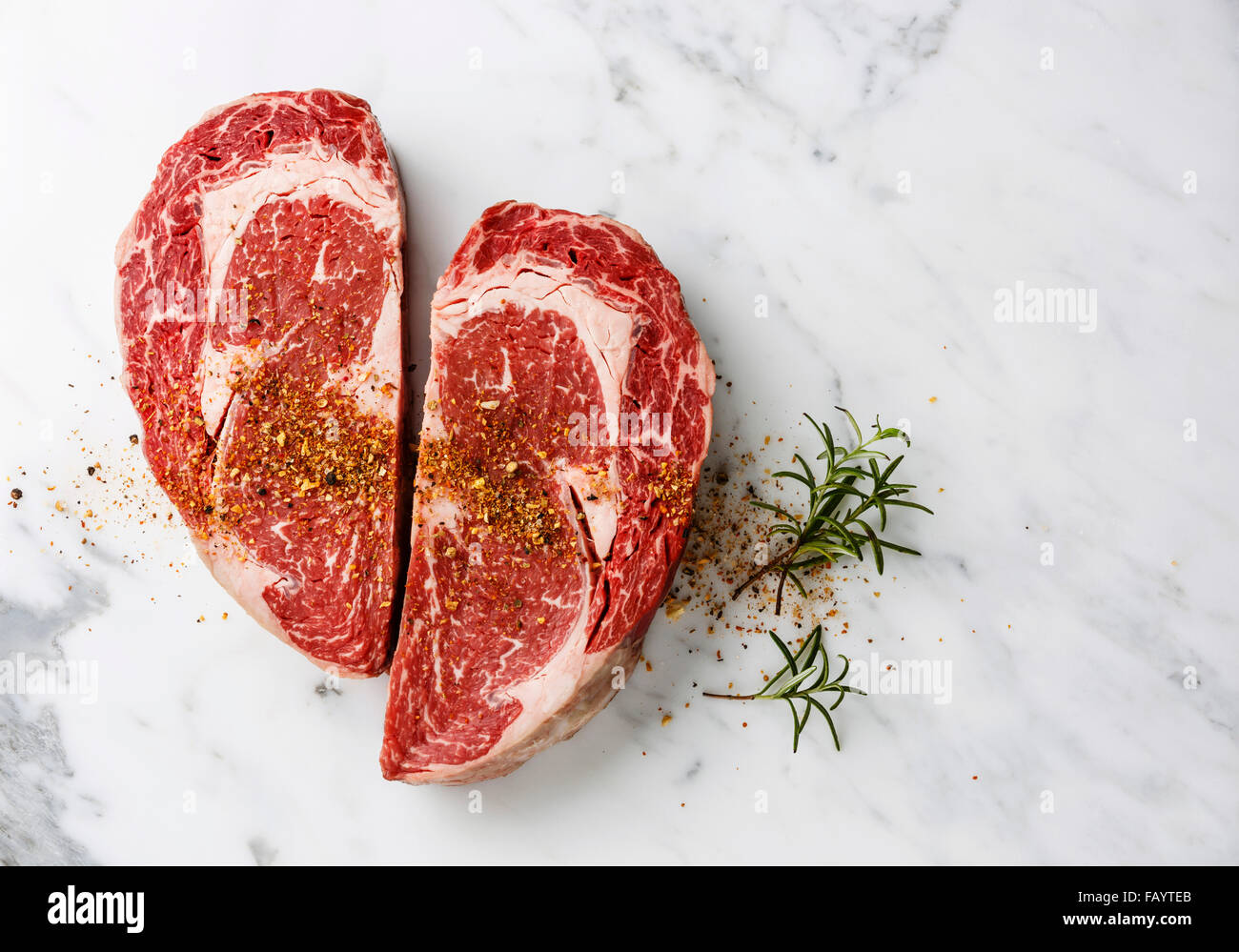 Herzform rohes Frischfleisch Ribeye Steak mit Würze auf weißem Marmor Hintergrund Stockfoto