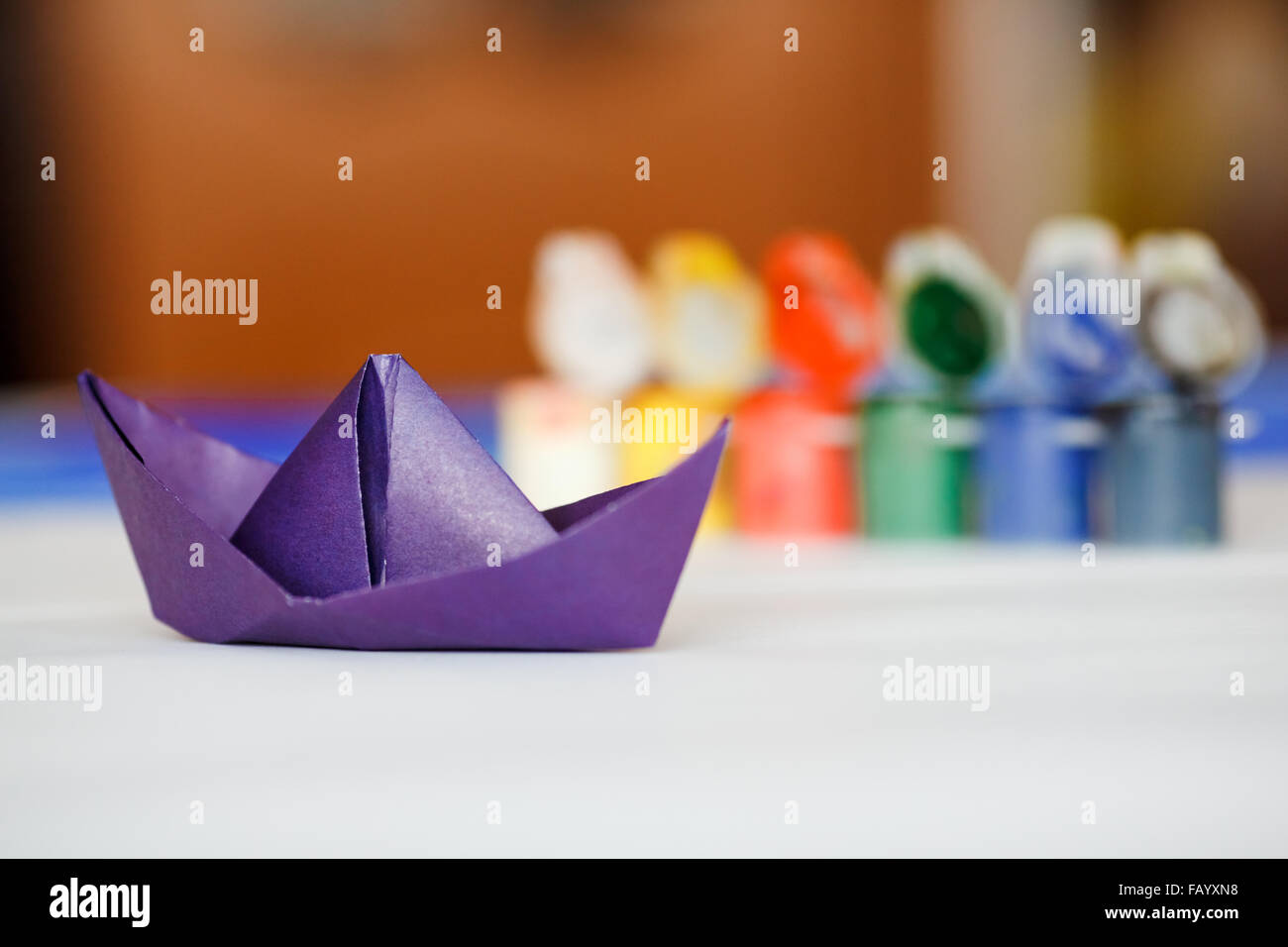 Origami Papier Boot Violett Farbe vor Gläser mit Multi farbige Lacke. Stockfoto