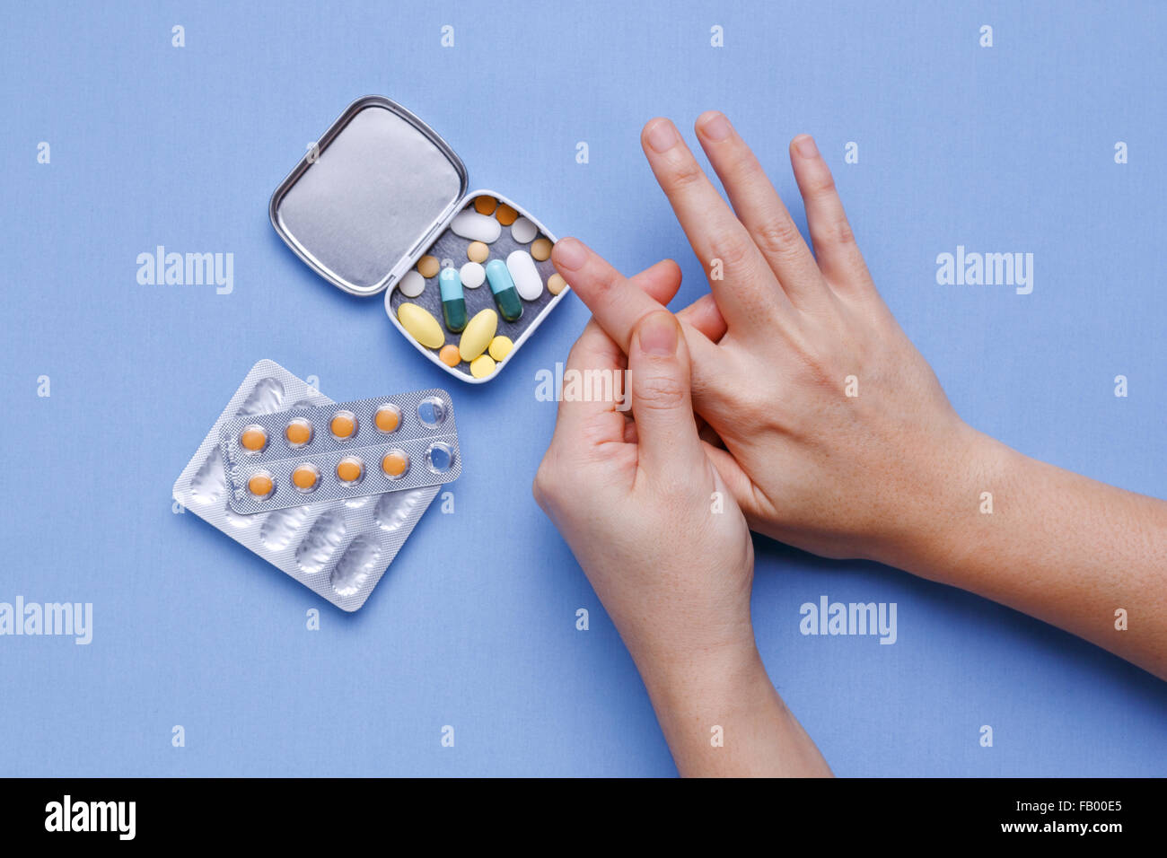 Frau Hand mit Finger Schmerzen und Pillen auf Tisch Stockfoto