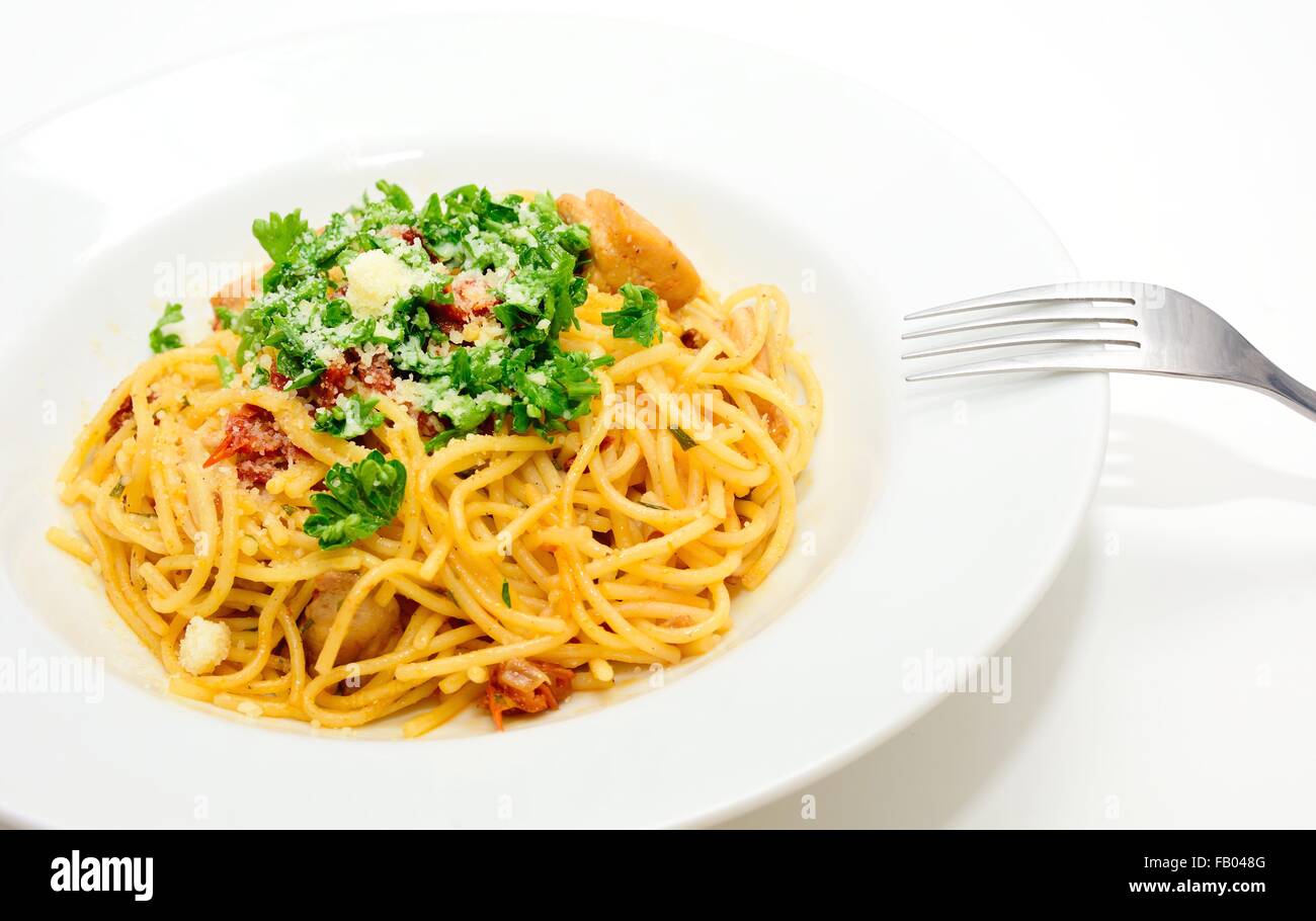 Spaghetti mit getrockneten Tomaten, Hühnerfleisch, Parmesan und mit Petersilie bestreut. Stockfoto
