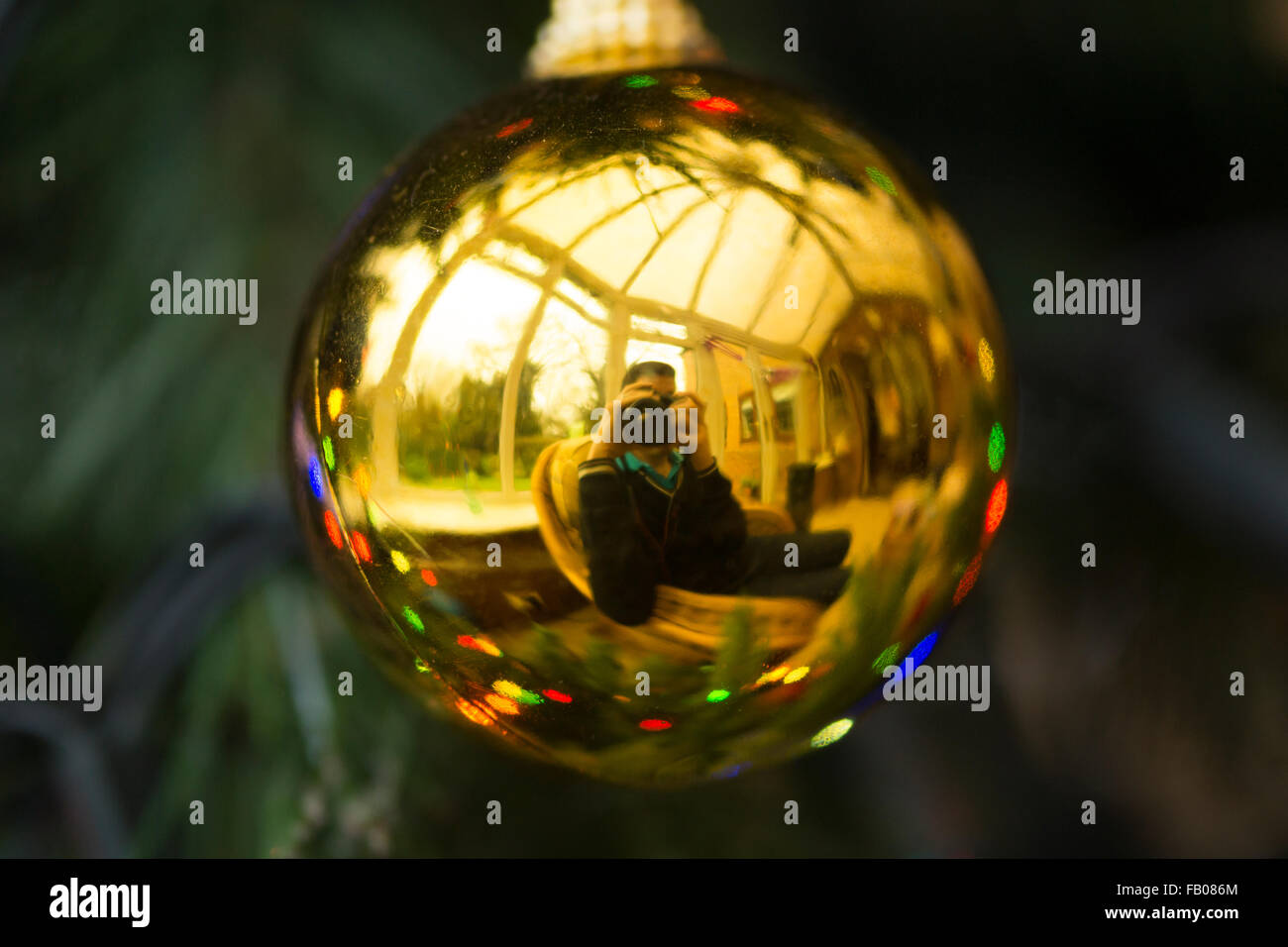 Eine reflektierte Ansicht eines Mannes in seinen Dreißigern, der nimmt Ein Foto (Selbstporträt) in einer Weihnachtsbaumkugel Stockfoto