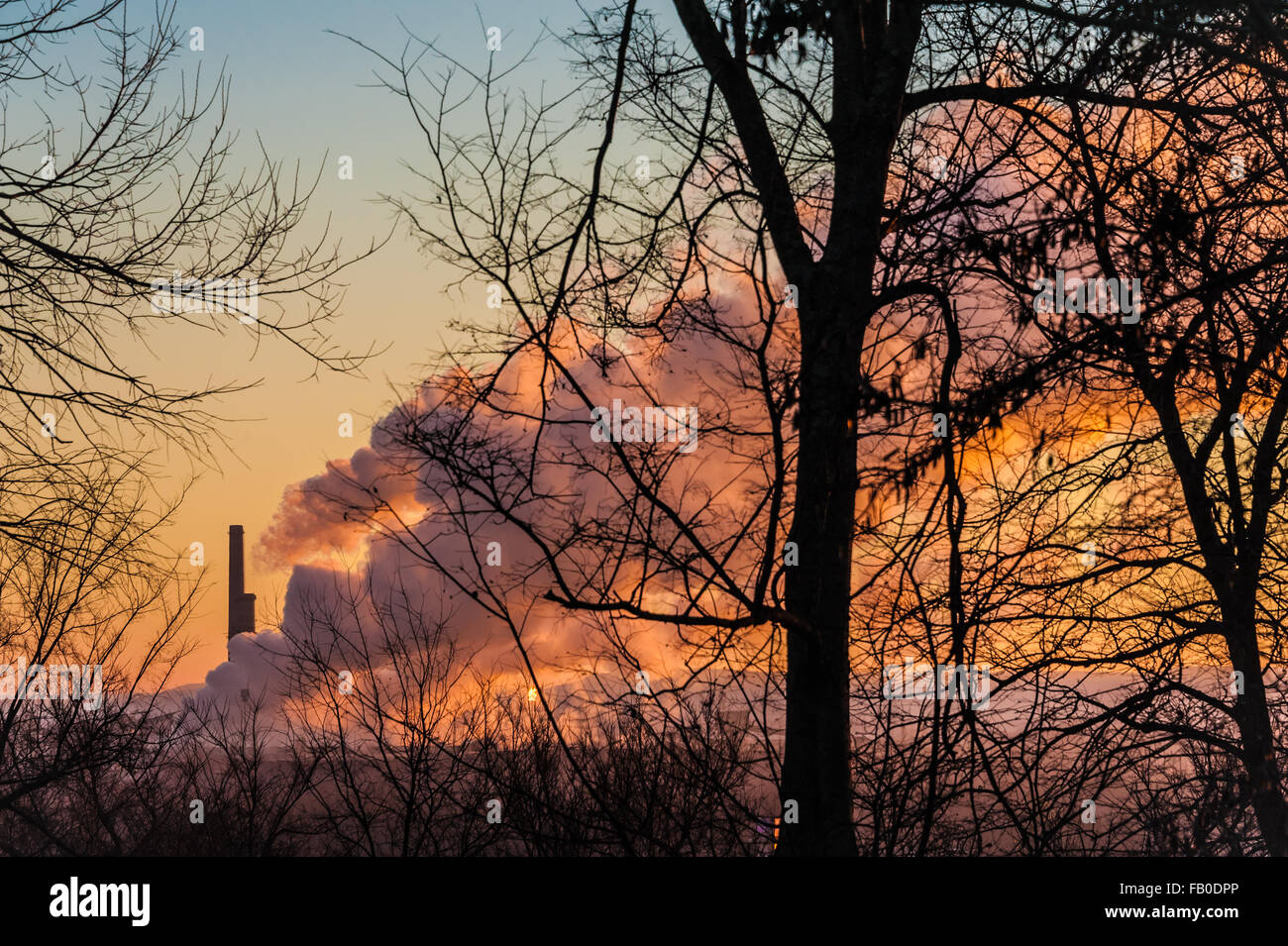 Leuchtende Sonnenaufgangsfarben bringen den Himmel zum Leuchten, und Dampf kommt aus dem KRAFTWERK OG&E Muskogee in Fort Gibson, Oklahoma. (USA) Stockfoto