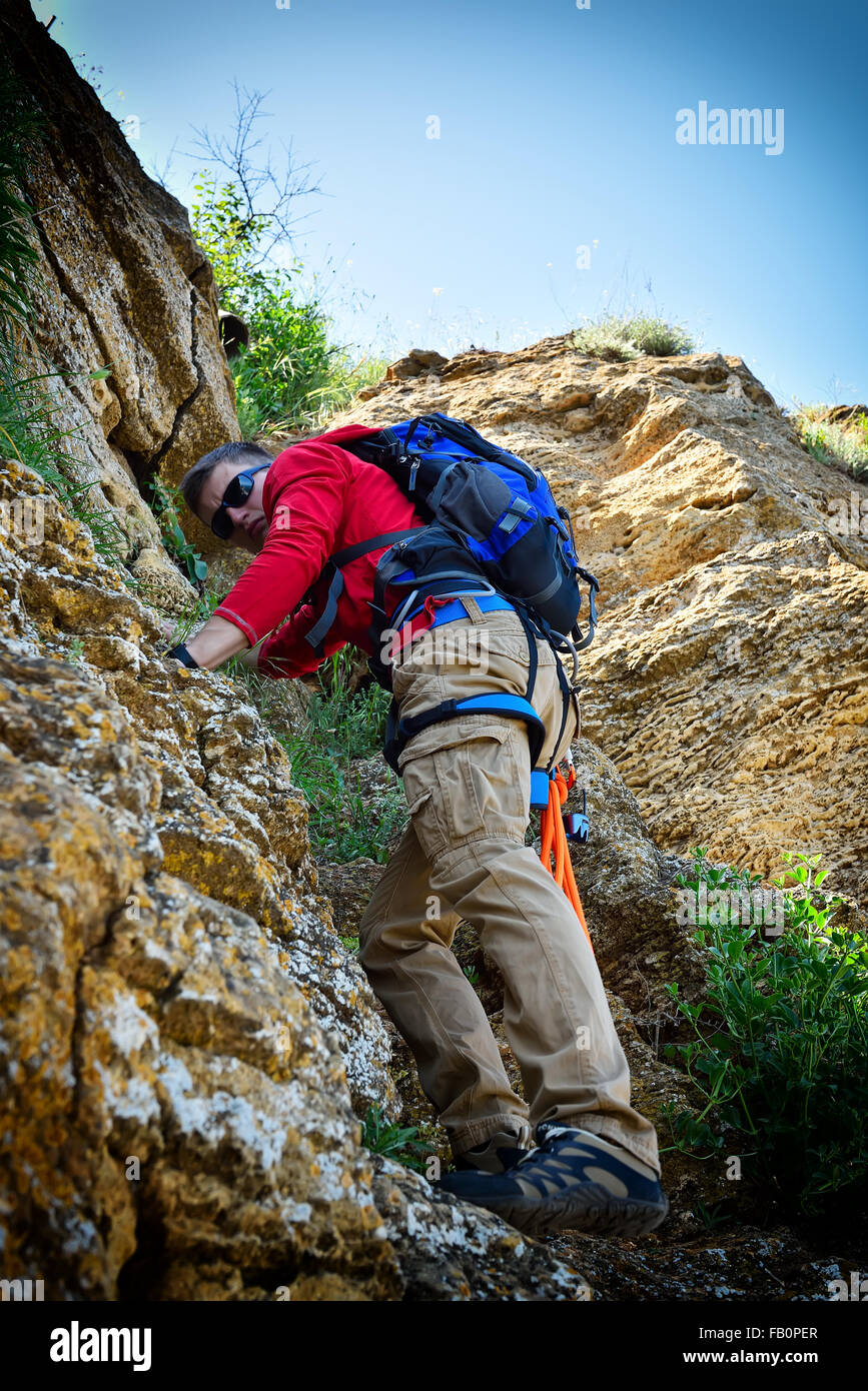 junge Bergsteiger mit Rucksack Klettern auf einer Klippe Stockfoto