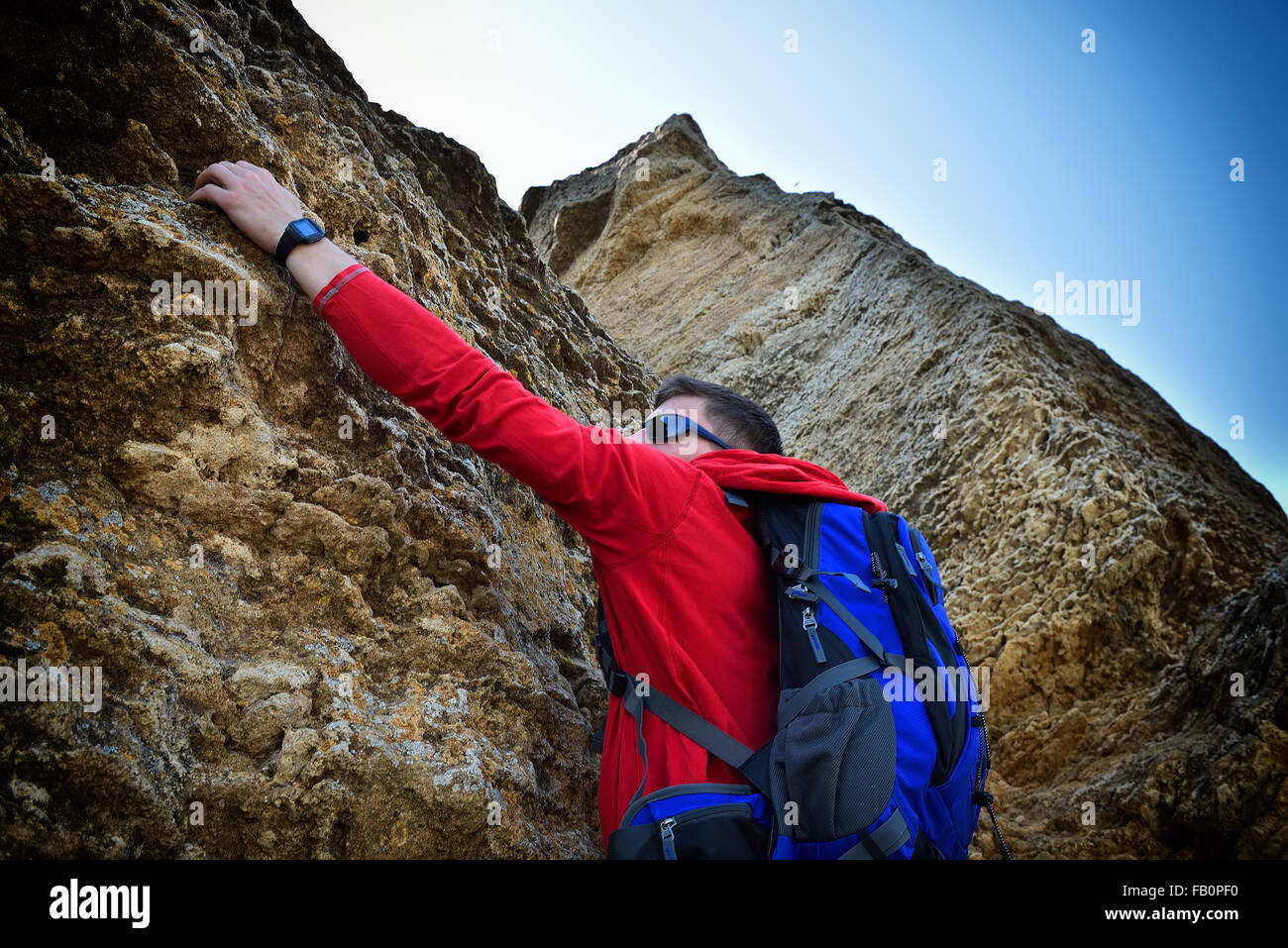 Kletterer Mann mit Rucksack hängen auf dem Felsen Stockfoto