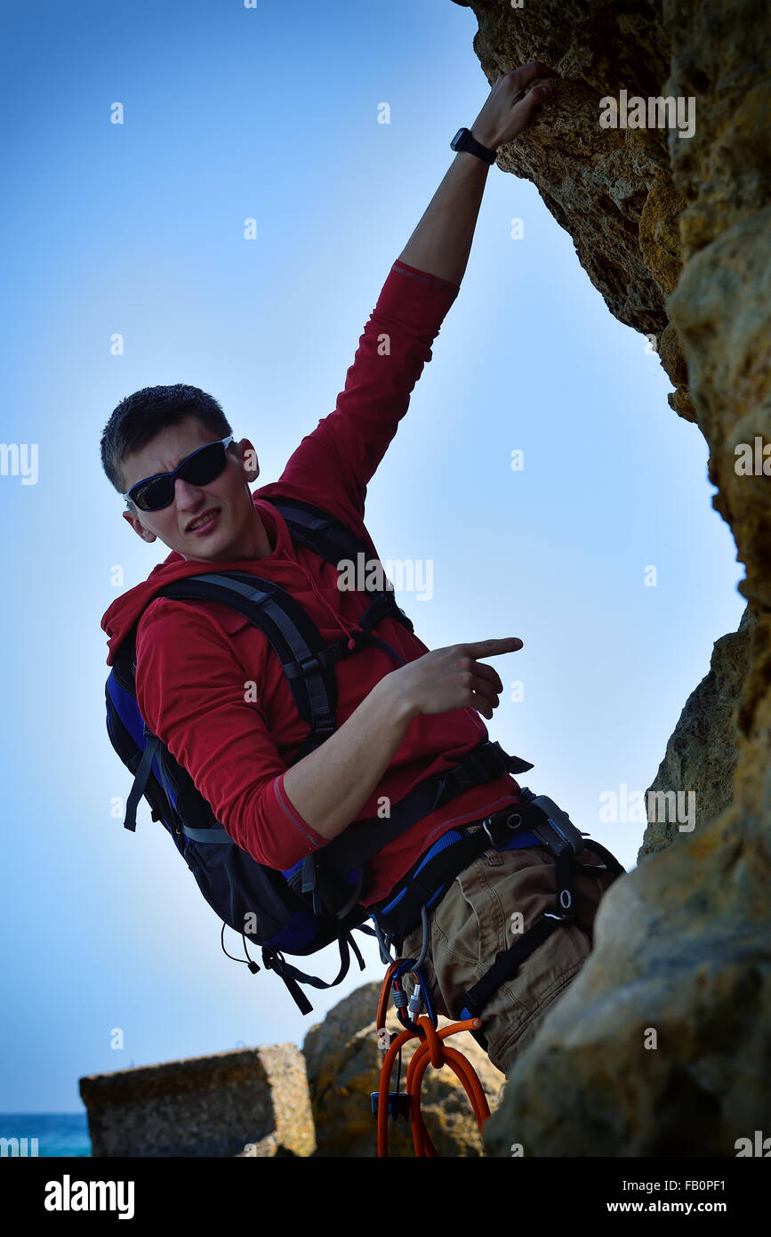 junge Bergsteiger mit Rucksack Klettern auf einer Klippe Stockfoto