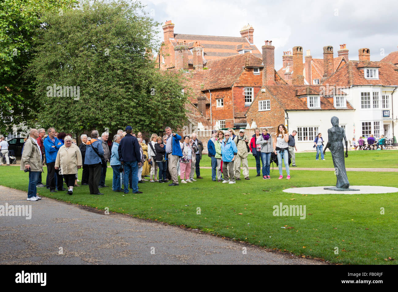 Eine Gruppe von Touristen mit einem Reiseführer versammelten sich in der Nähe von Walking Madonna Statue (1981) von Elisabeth Frink in Salisbury Cathedral. Stockfoto