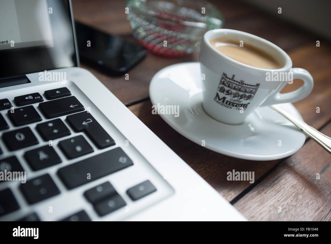 Espresso-Kaffee auf eine Designer-Schreibtisch platziert neben einem Laptop-Computer und Handy in einem Heim Arbeitsumfeld. Stockfoto