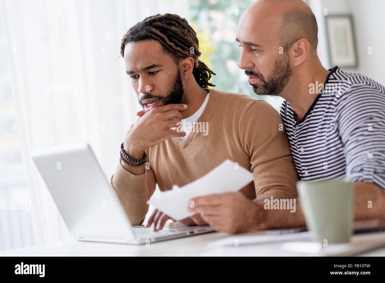 Zwei Männer arbeiten mit Laptop am Tisch zu Hause Stockfoto