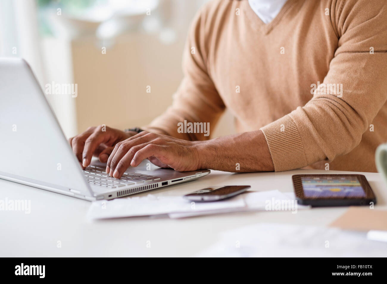 Mann mit Laptop am Tisch zu Hause arbeiten Stockfoto