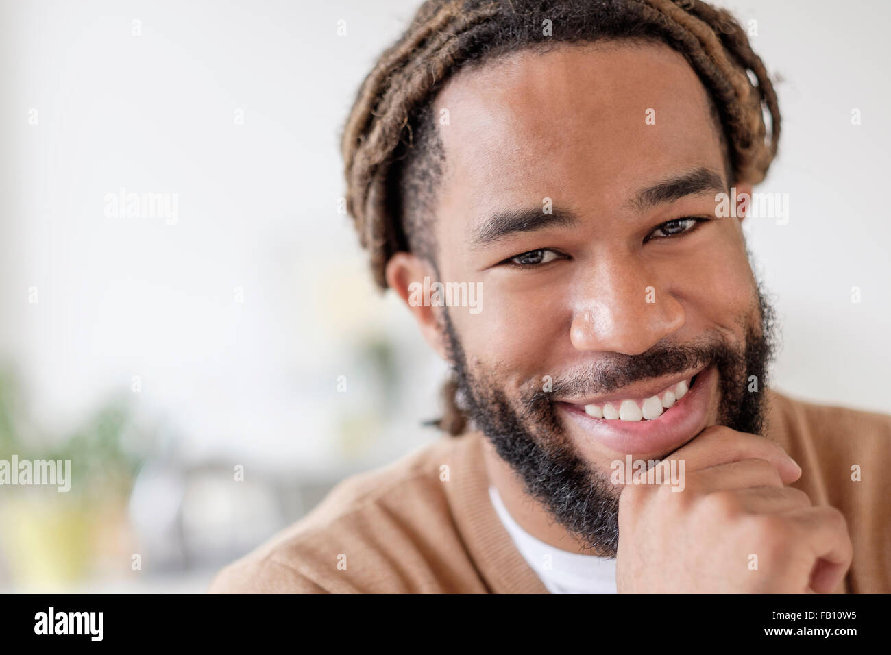 Porträt von Smiley junger Mann mit Hand am Kinn Stockfoto