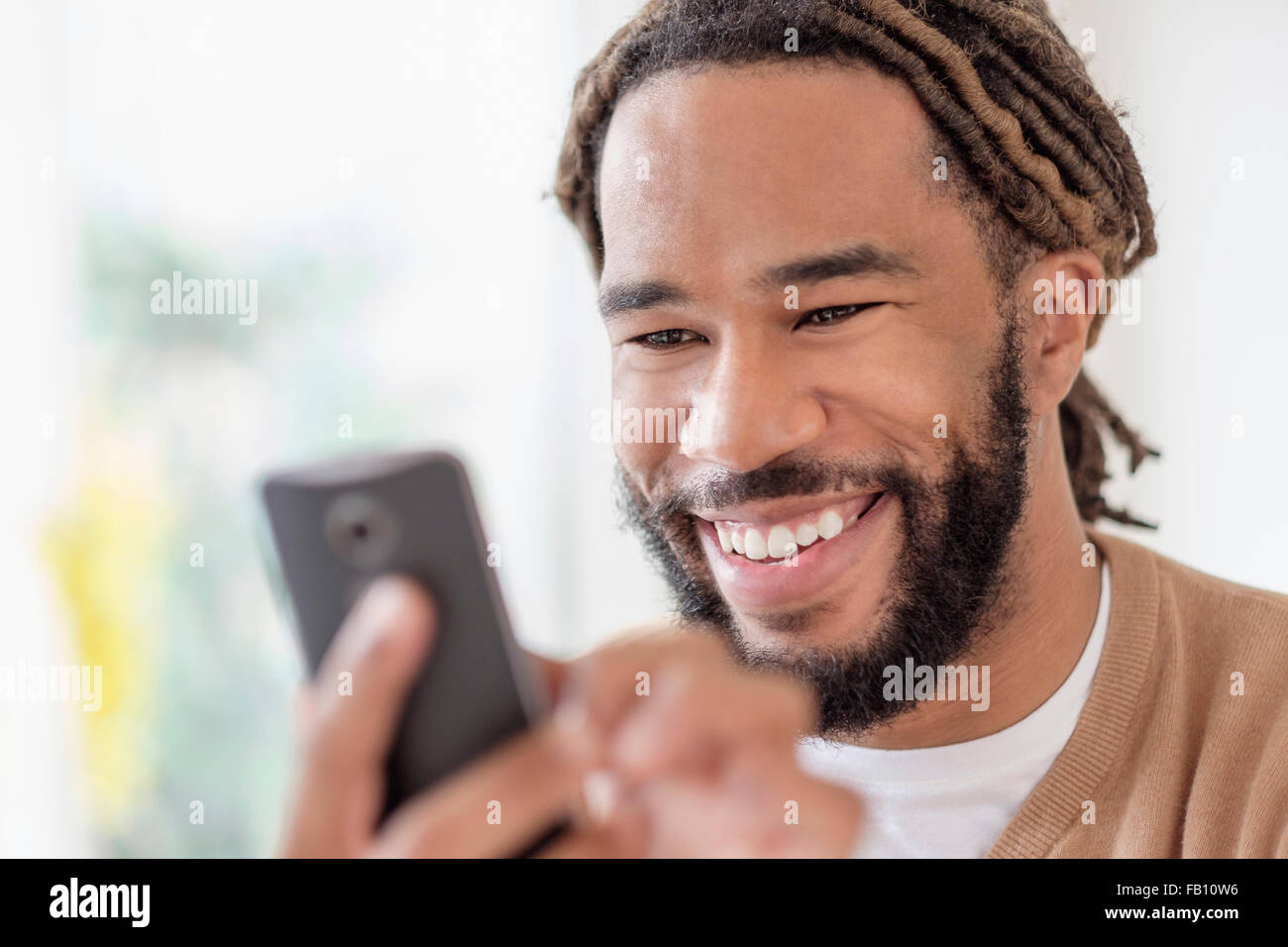 Smiley junger Mann mit Dreadlocks mit Smartphone Stockfoto