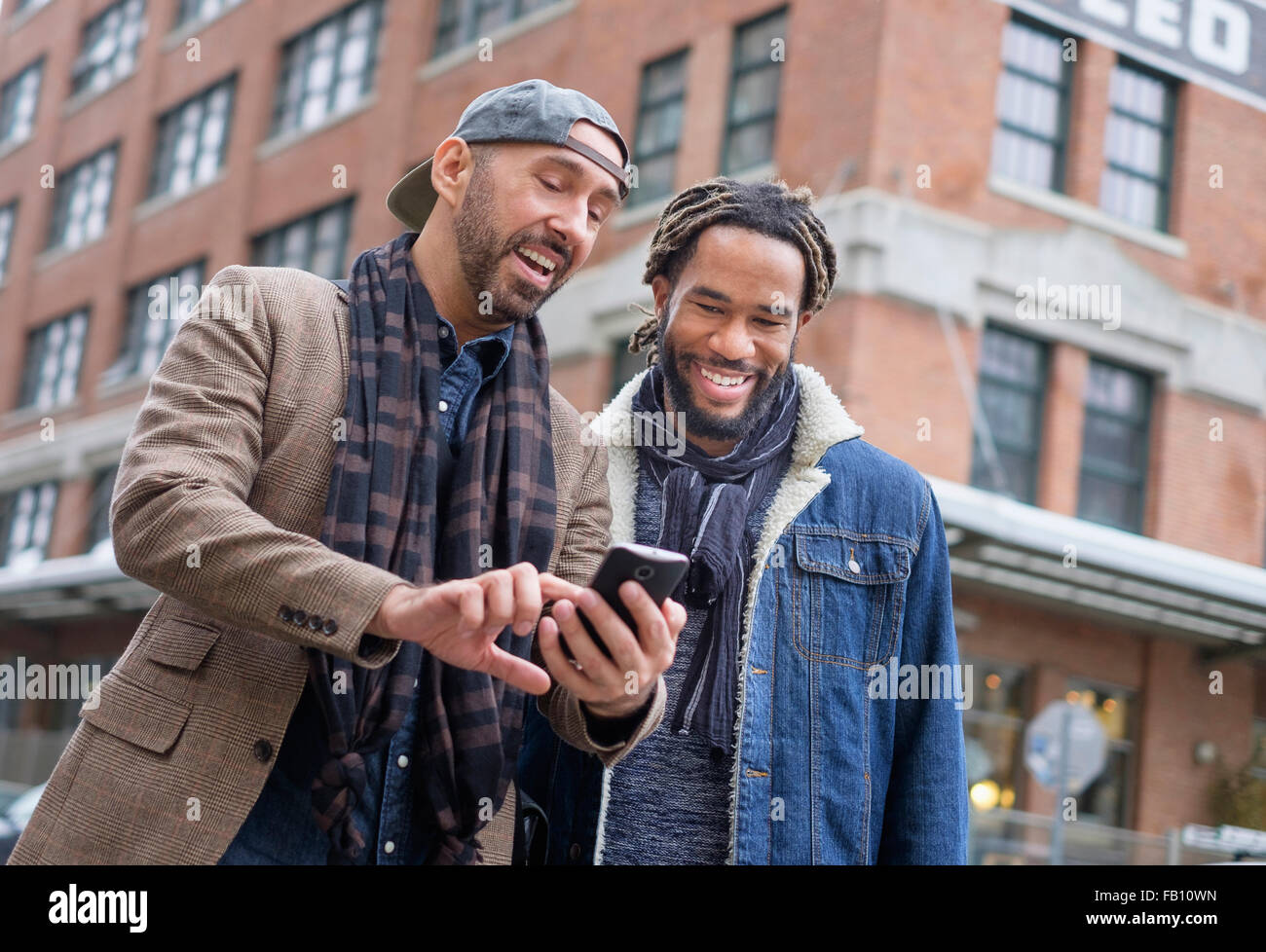 Smiley homosexuelles Paar Blick auf Smartphone auf Straße Stockfoto