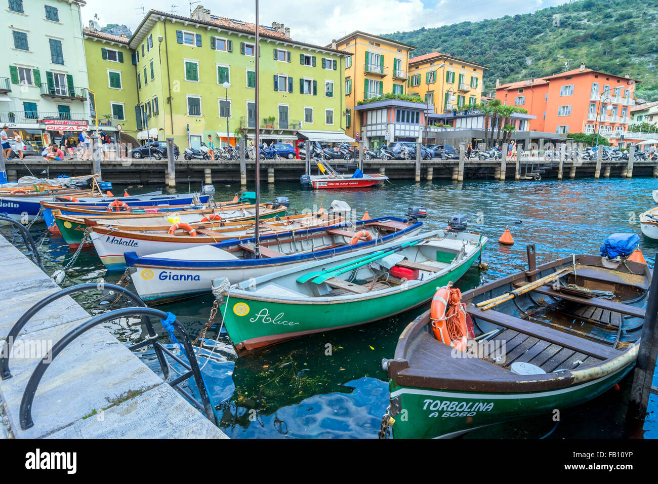 Gardasee-Promenade mit Häusern, Touristen und Boote in Torbole, Italien. Stockfoto