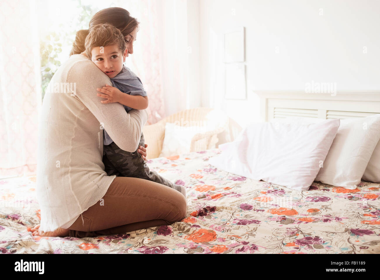 Mutter umarmt Sohn (2-3) auf Bett Stockfoto