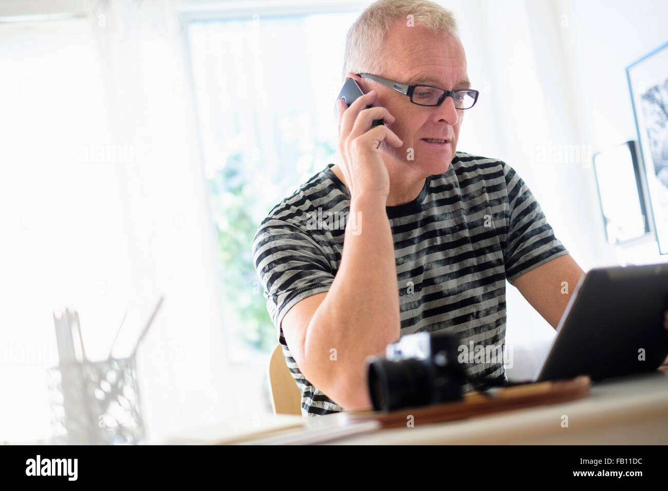 Mann im home-Office mit Smartphone und tablet Stockfoto