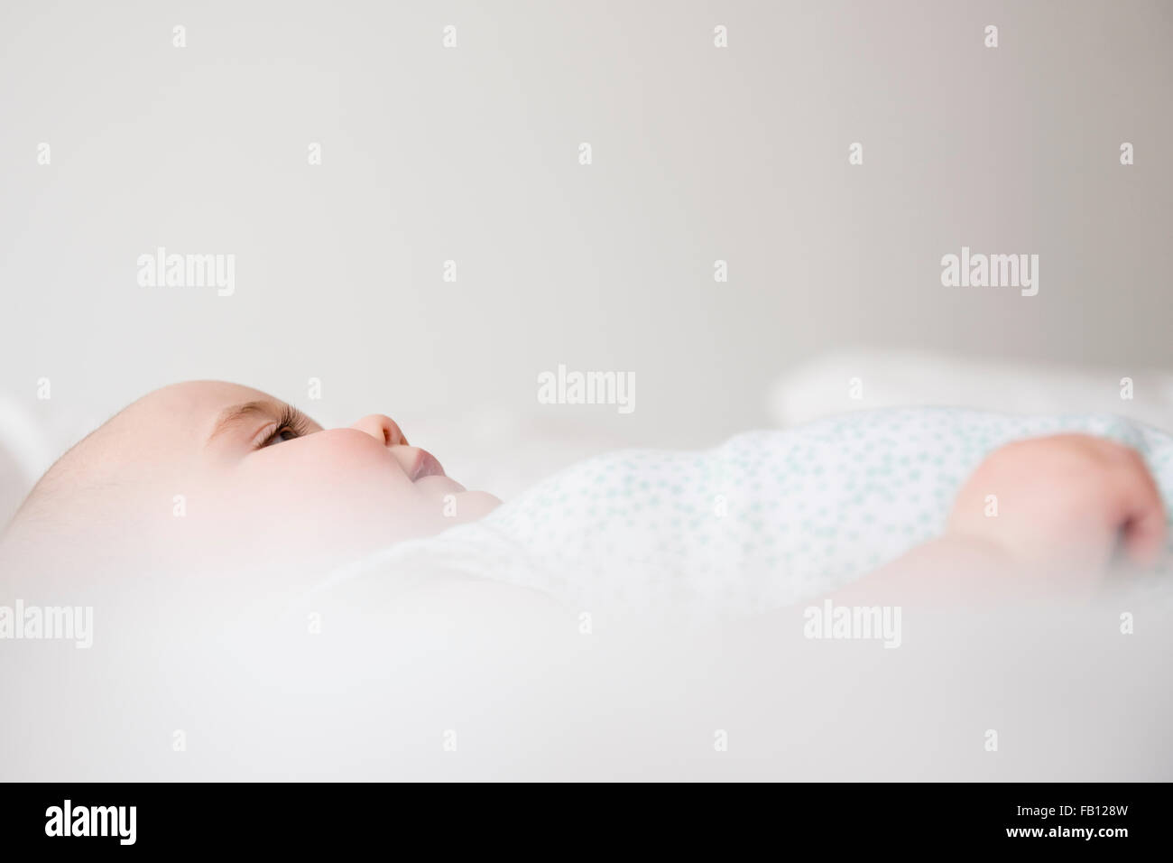 Babymädchen (12-17 Monate) auf Bett liegend Stockfoto