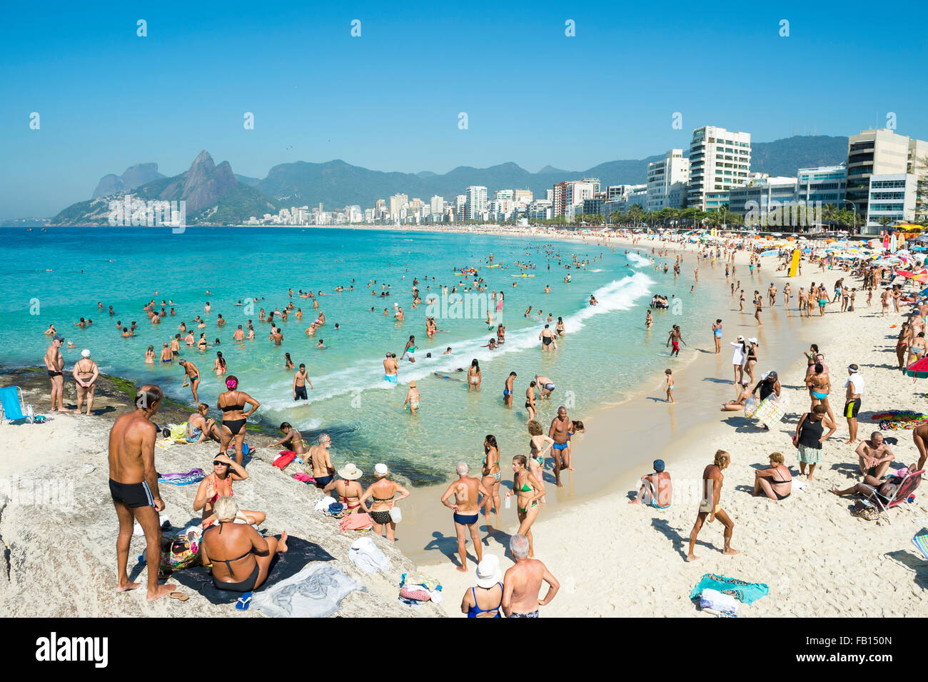 RIO DE JANEIRO, Brasilien - 8. Februar 2015: Beachgoers nutzen ruhige See am Arpoador Ende der Strand von Ipanema. Stockfoto