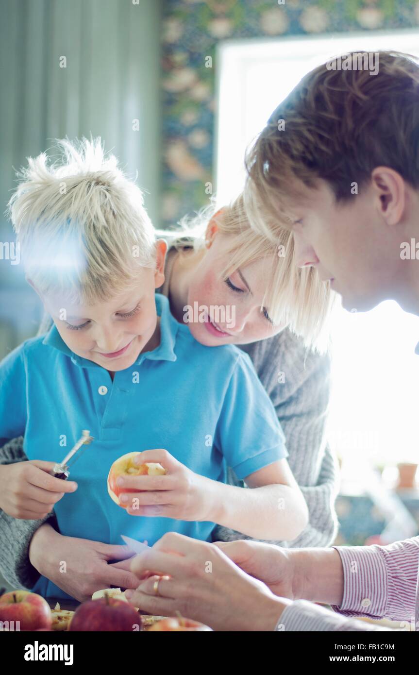 Eltern und Sohn peeling Bio-Äpfel in Küche Stockfoto