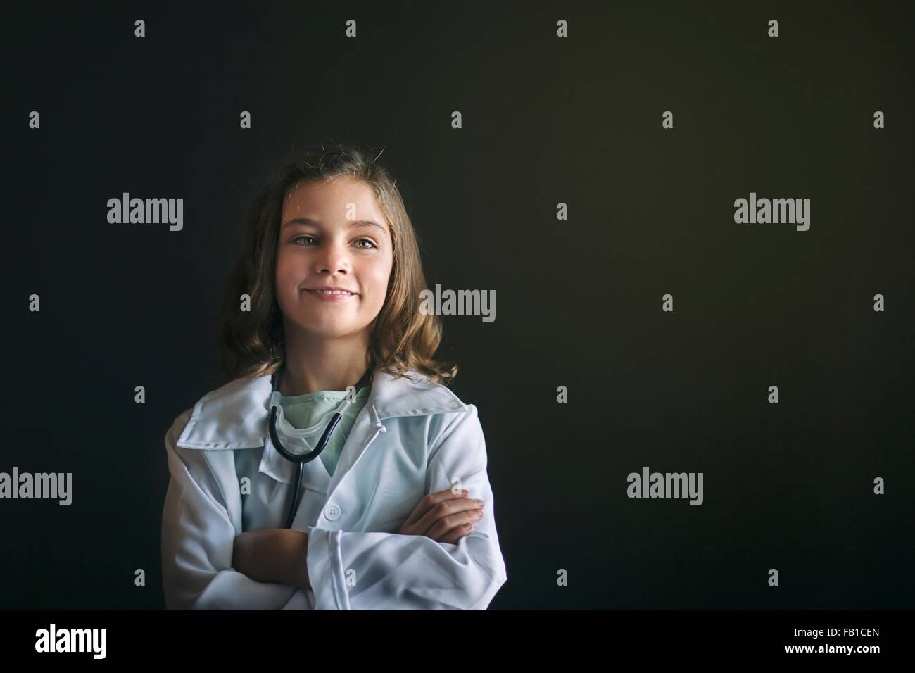 Porträt von Mädchen verkleidete sich als Arzt mit Stethoskop, verschränkte Arme aussehenden Weg Lächeln Stockfoto